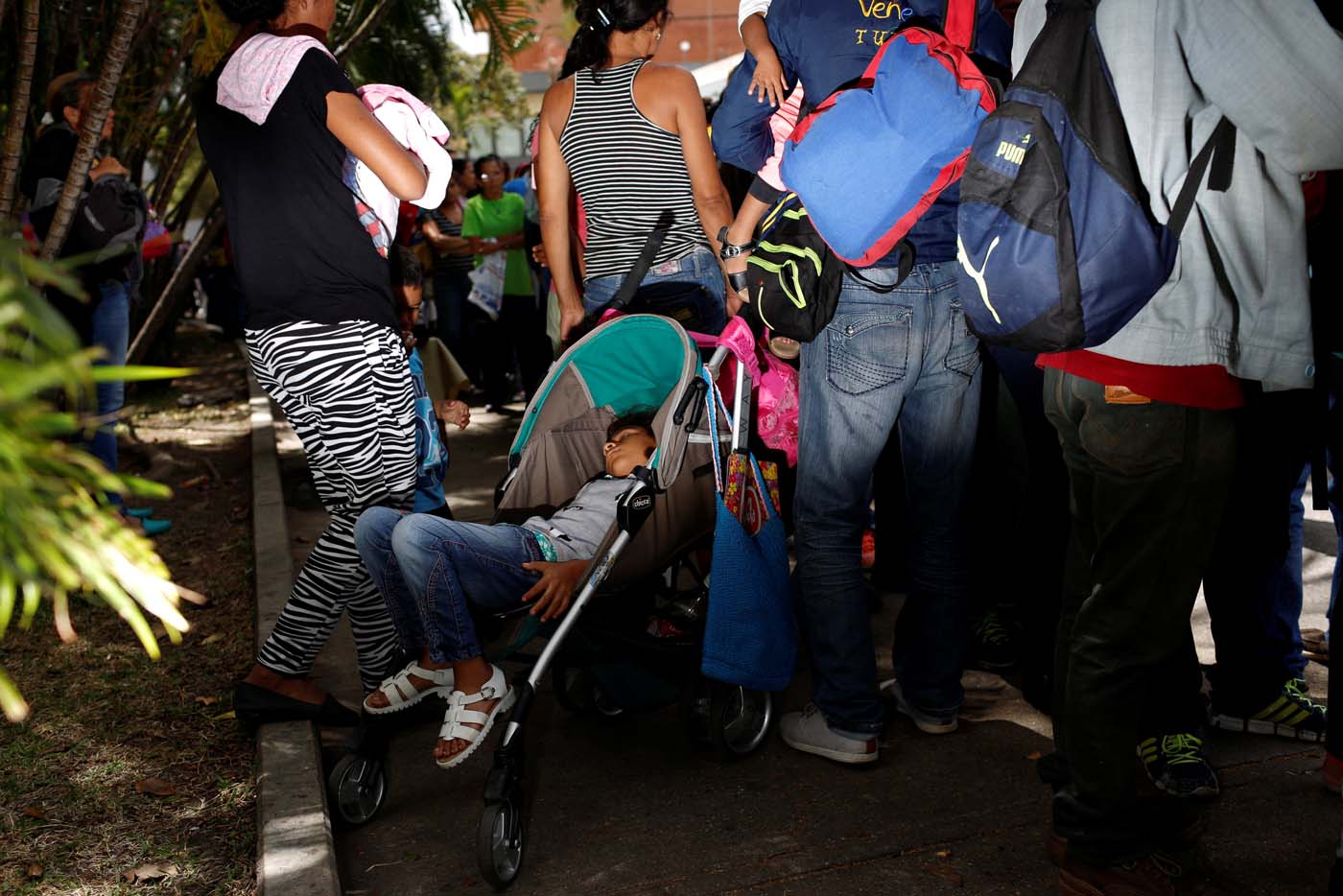 A girl sleeps in a baby stroller next to her mother while they queue to try and buy food outside a supermarket in Caracas, Venezuela March 10, 2017. REUTERS/Carlos Garcia Rawlins SEARCH "GARCIA QUEUEING" FOR THIS STORY. SEARCH "WIDER IMAGE" FOR ALL STORIES.