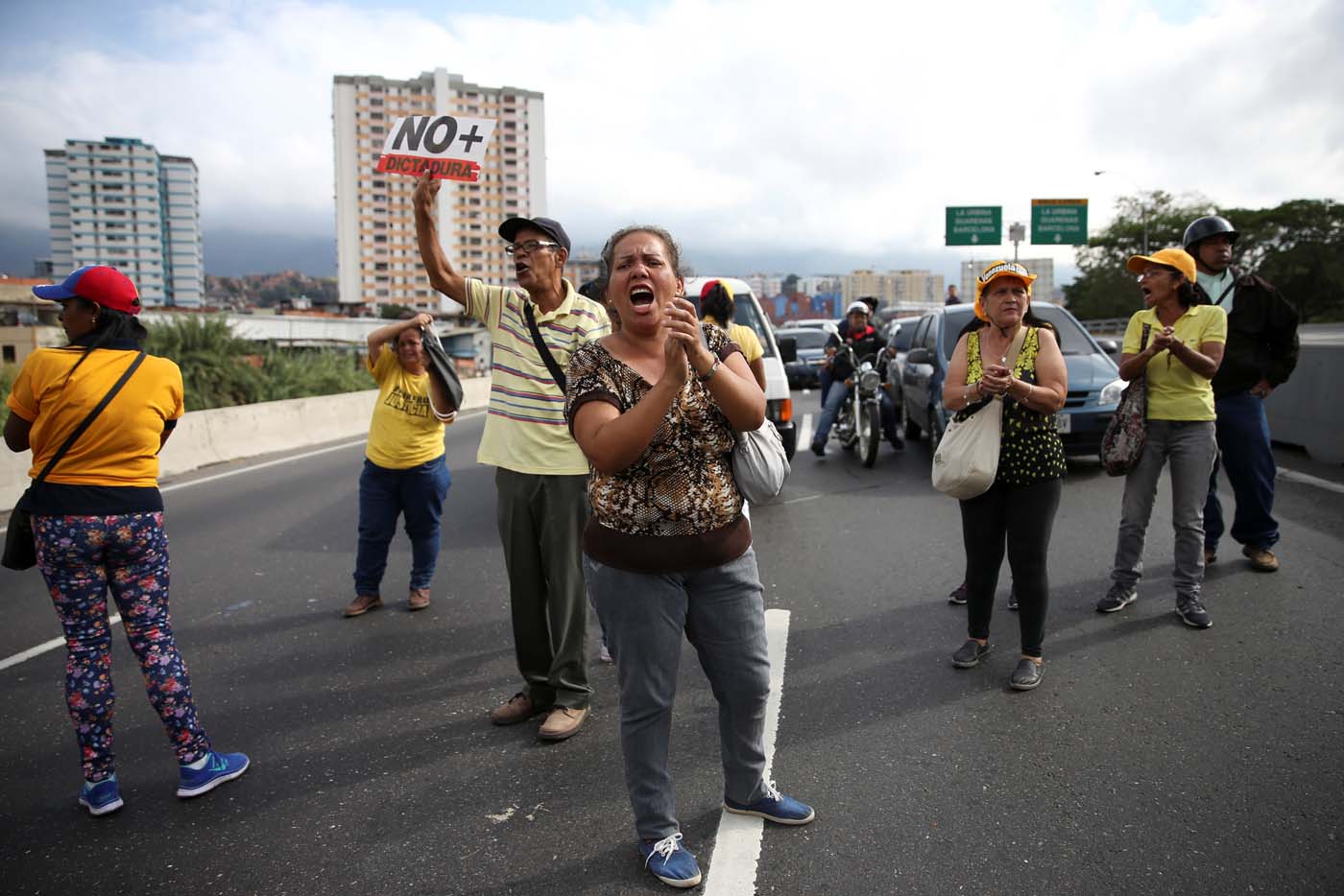 Opposition supporters holding a placard that reads, "No more dictatorship" shout slogans as they block a highway during a protest against Venezuelan President Nicolas Maduro's government in Caracas, Venezuela March 31, 2017. REUTERS/Carlos Garcia Rawlins