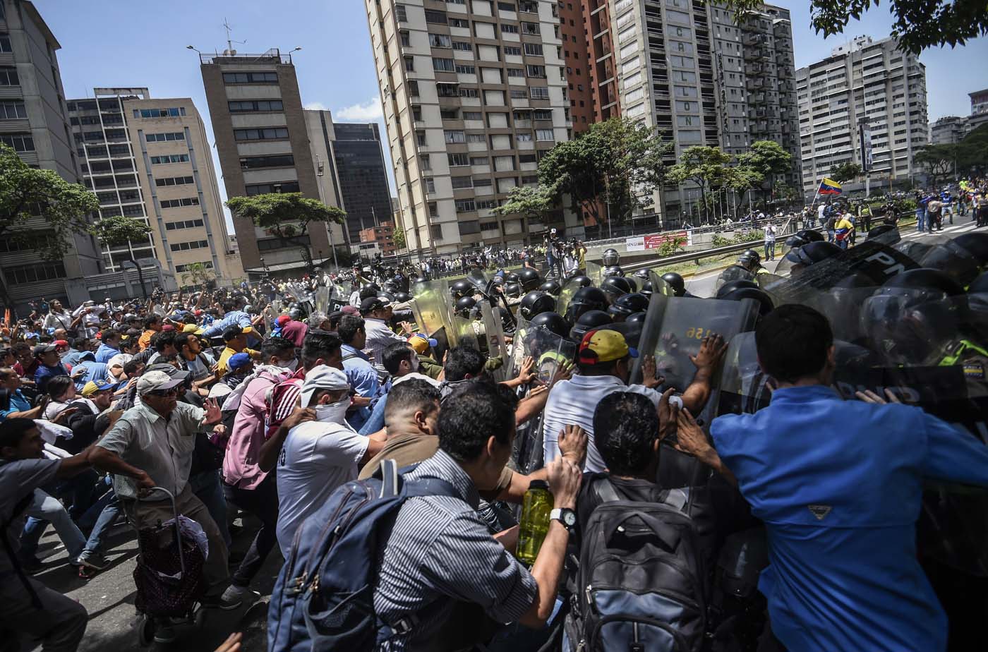Venezuela's opposition activists clash with riot police agents during a protest against Nicolas Maduro's government in Caracas on April 4, 2017. Protesters clashed with police in Venezuela Tuesday as the opposition mobilized against moves to tighten President Nicolas Maduro's grip on power. Protesters hurled stones at riot police who fired tear gas as they blocked the demonstrators from advancing through central Caracas, where pro-government activists were also planning to march. / AFP PHOTO / JUAN BARRETO