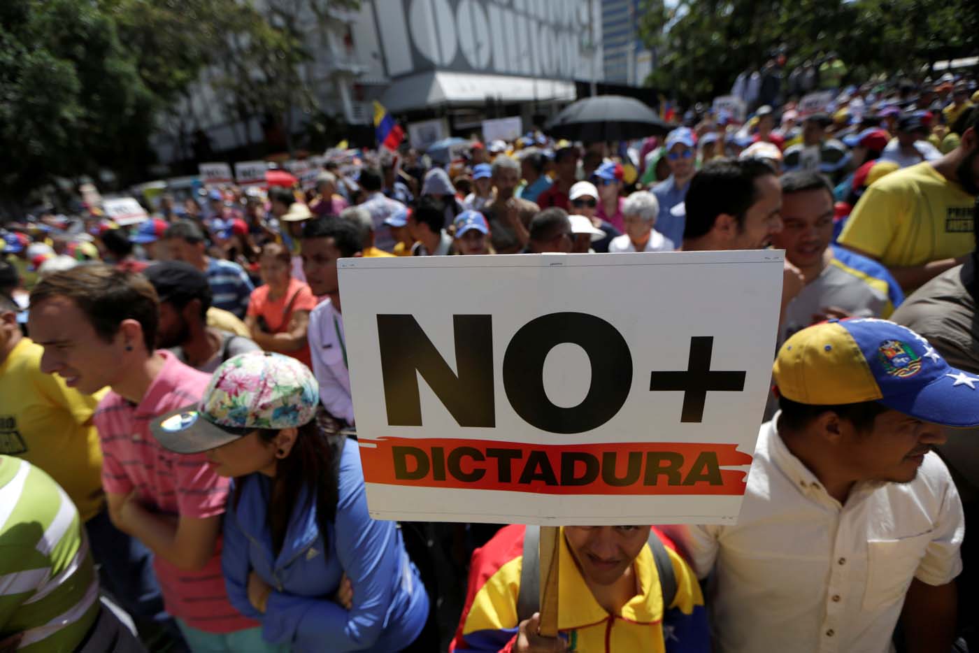 An opposition supporter holds a placard that reads "No more dictatorship" as he takes part in a rally against Venezuela's President Nicolas Maduro's government in Caracas, Venezuela April 1, 2017. REUTERS/Marco Bello