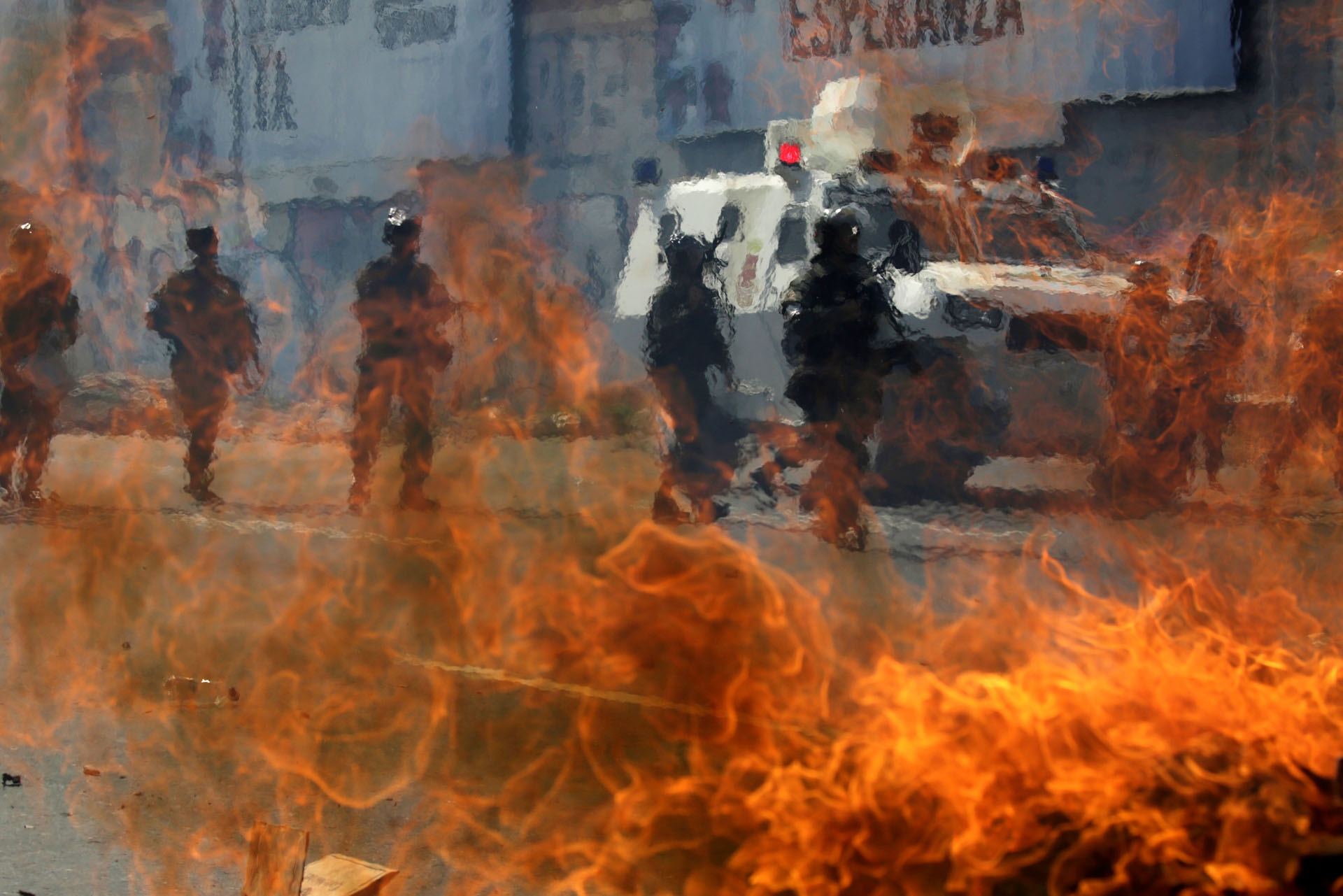 Venezuelan national guards walk behind a burning blockade during clashes with demonstrators during an opposition rally in Caracas, Venezuela, April 6, 2017. REUTERS/Marcos Bello
