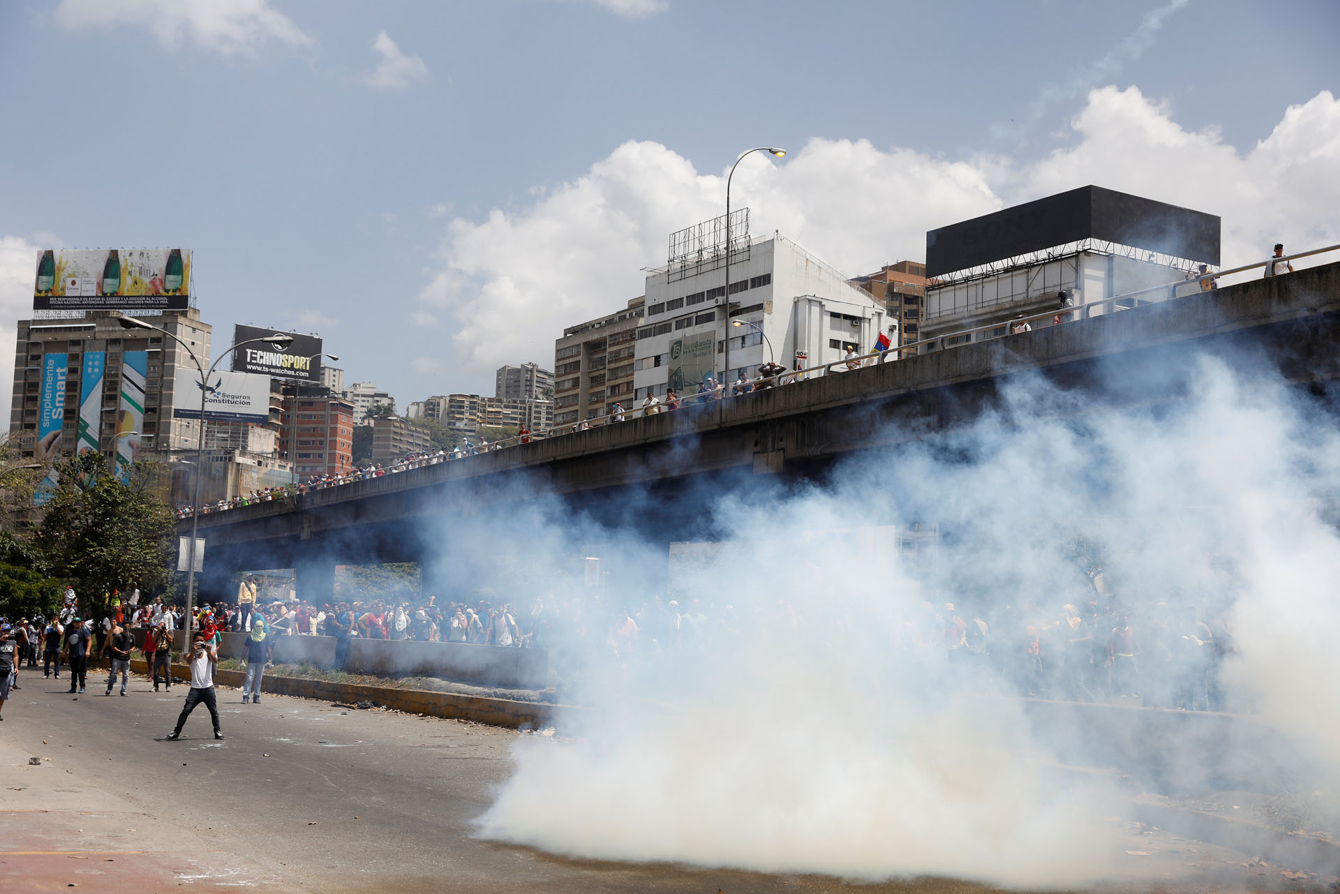 Demonstrators stay away from tear gas fired by security forces during an opposition rally in Caracas, Venezuela April 6, 2017. REUTERS/Carlos Garcia Rawlins