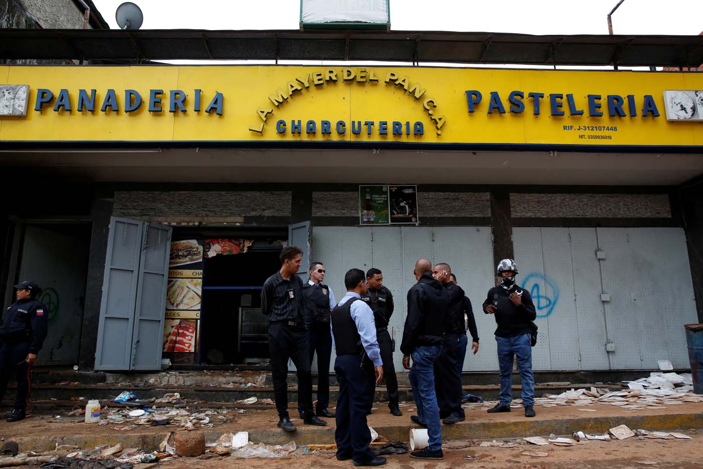 REFILE - UPDATING SLUG Police officers and criminal investigators stand in front of a bakery, after it was looted in Caracas, Venezuela April 21, 2017. REUTERS/Carlos Garcia Rawlins