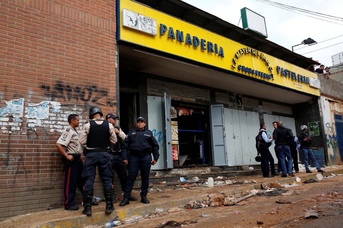 Police officers and criminal investigators stand in front of a bakery, after it was looted in Caracas, Venezuela April 21, 2017. REUTERS/Carlos Garcia Rawlins