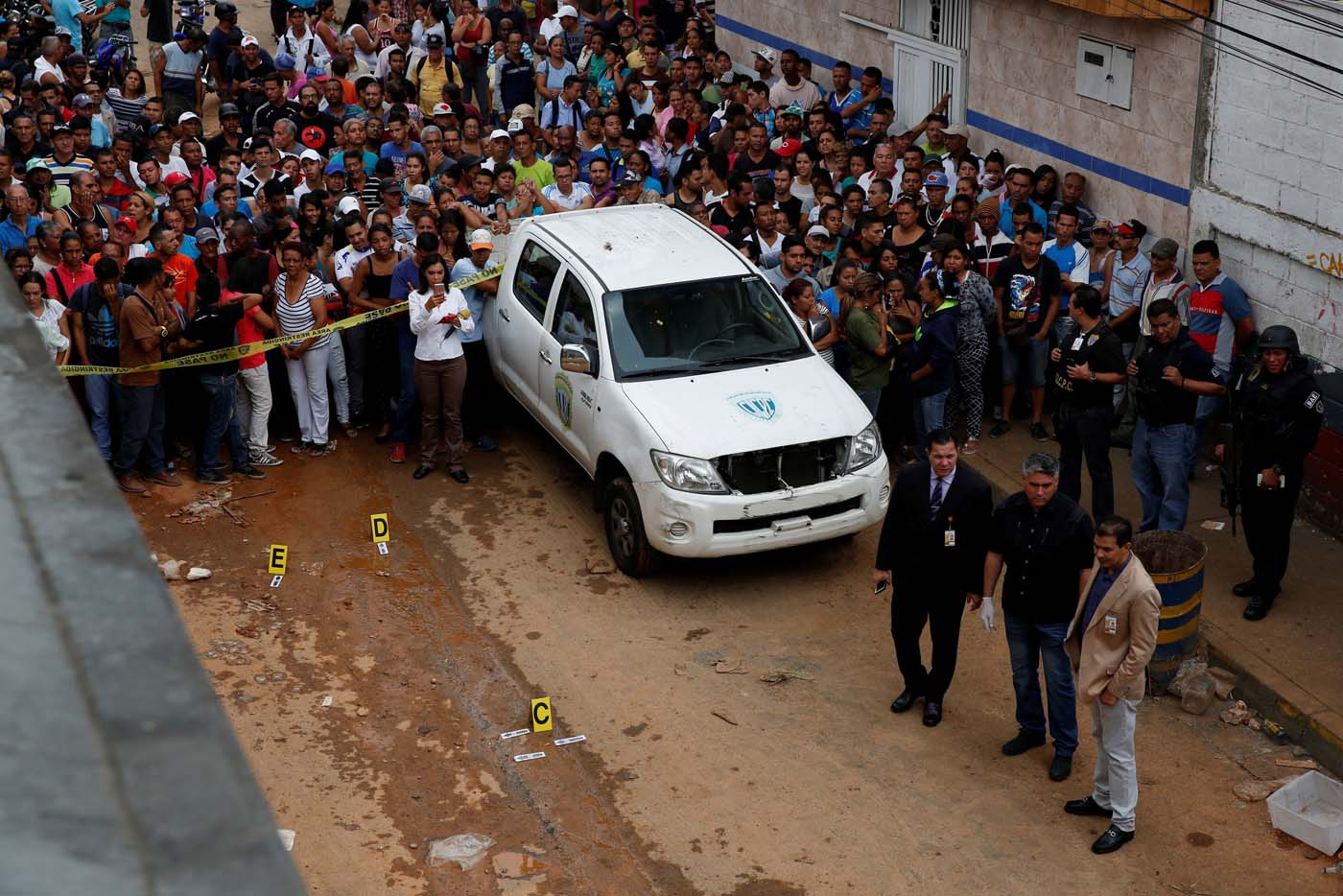 People look at police officers and criminal investigators while they collect evidence in front of a bakery, after it was looted in Caracas, Venezuela April 21, 2017. REUTERS/Carlos Garcia Rawlins