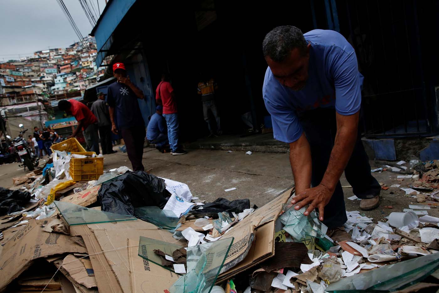 A man discards broken glass, while he tries to cleans his stall at a commercial street, after it was looted in Caracas, Venezuela April 21, 2017. REUTERS/Carlos Garcia Rawlins