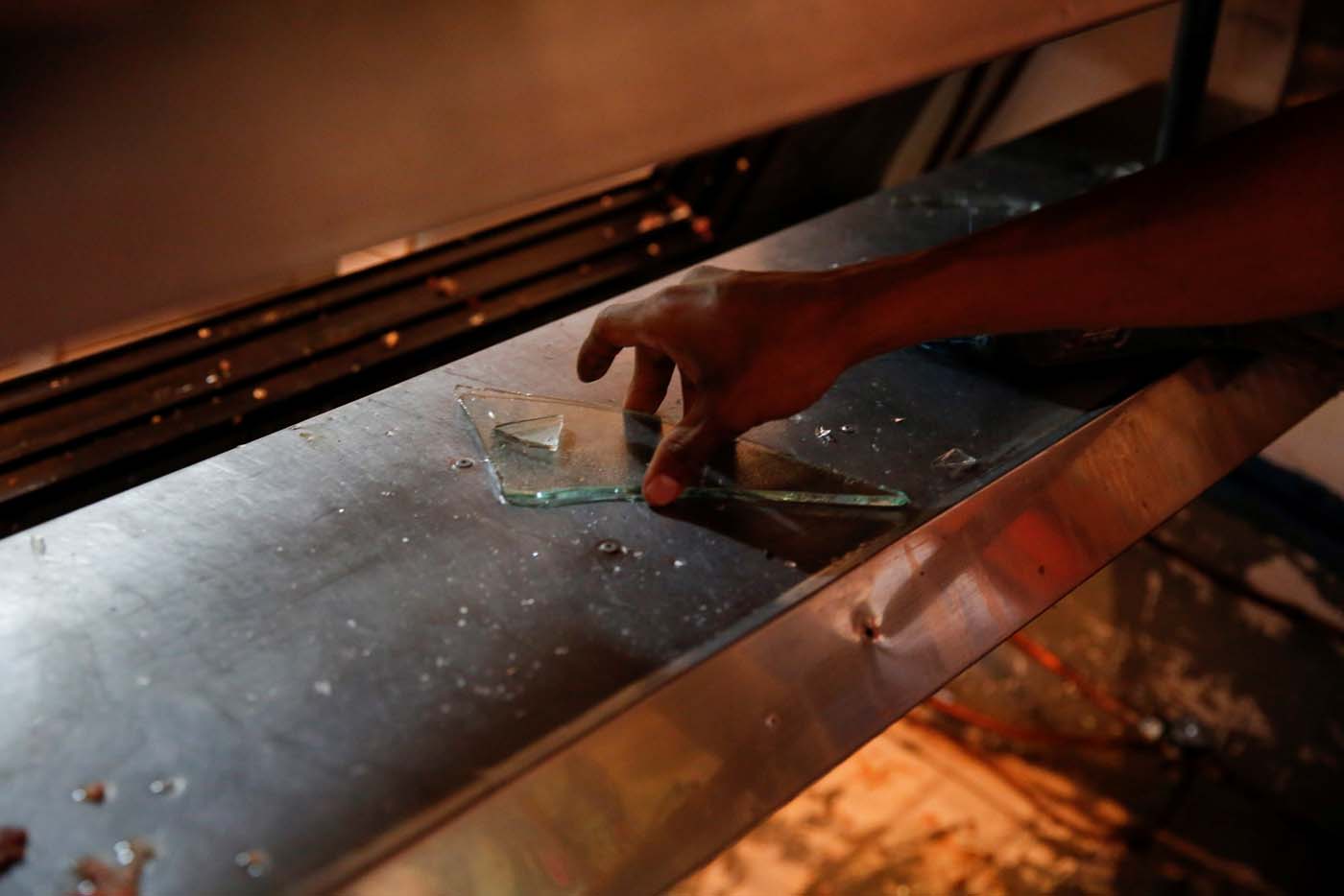 A man grabs pieces of glass from a broken refrigerator after a butcher's stall was looted in Caracas, Venezuela April 21, 2017. REUTERS/Carlos Garcia Rawlins