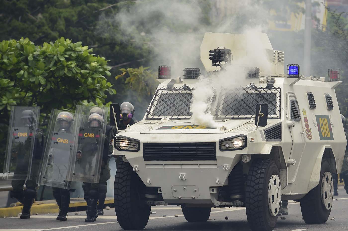 Riot police agents next to an armoured vehicle move forward along a blocked street, during clashes within a protest against Venezuelan President Nicolas Maduro, in Caracas on May 3, 2017. Venezuela's angry opposition rallied Wednesday vowing huge street protests against President Nicolas Maduro's plan to rewrite the constitution and accusing him of dodging elections to cling to power despite deadly unrest. / AFP PHOTO / RONALDO SCHEMIDT