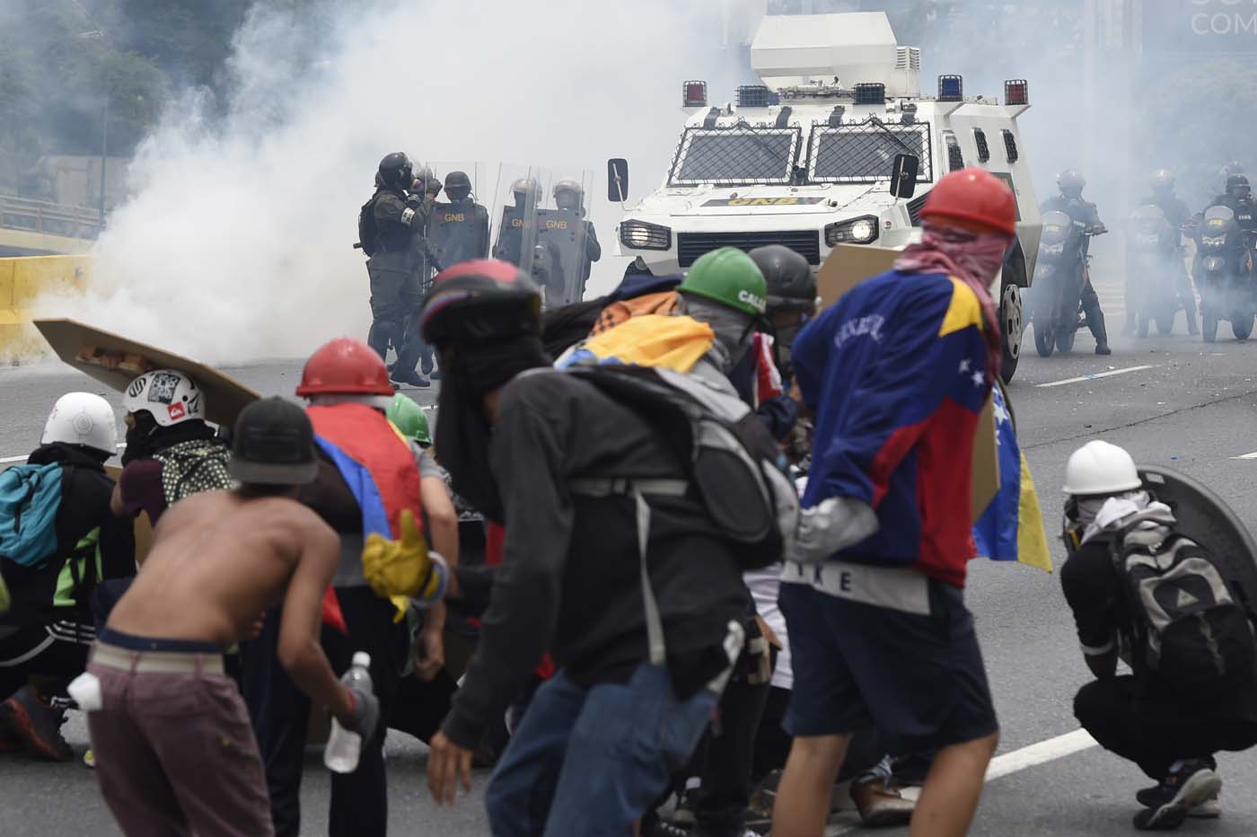 Demonstrators clash with riot police during a protest against Venezuelan President Nicolas Maduro, in Caracas on May 3, 2017. Venezuela's angry opposition rallied Wednesday vowing huge street protests against President Nicolas Maduro's plan to rewrite the constitution and accusing him of dodging elections to cling to power despite deadly unrest. / AFP PHOTO / JUAN BARRETO