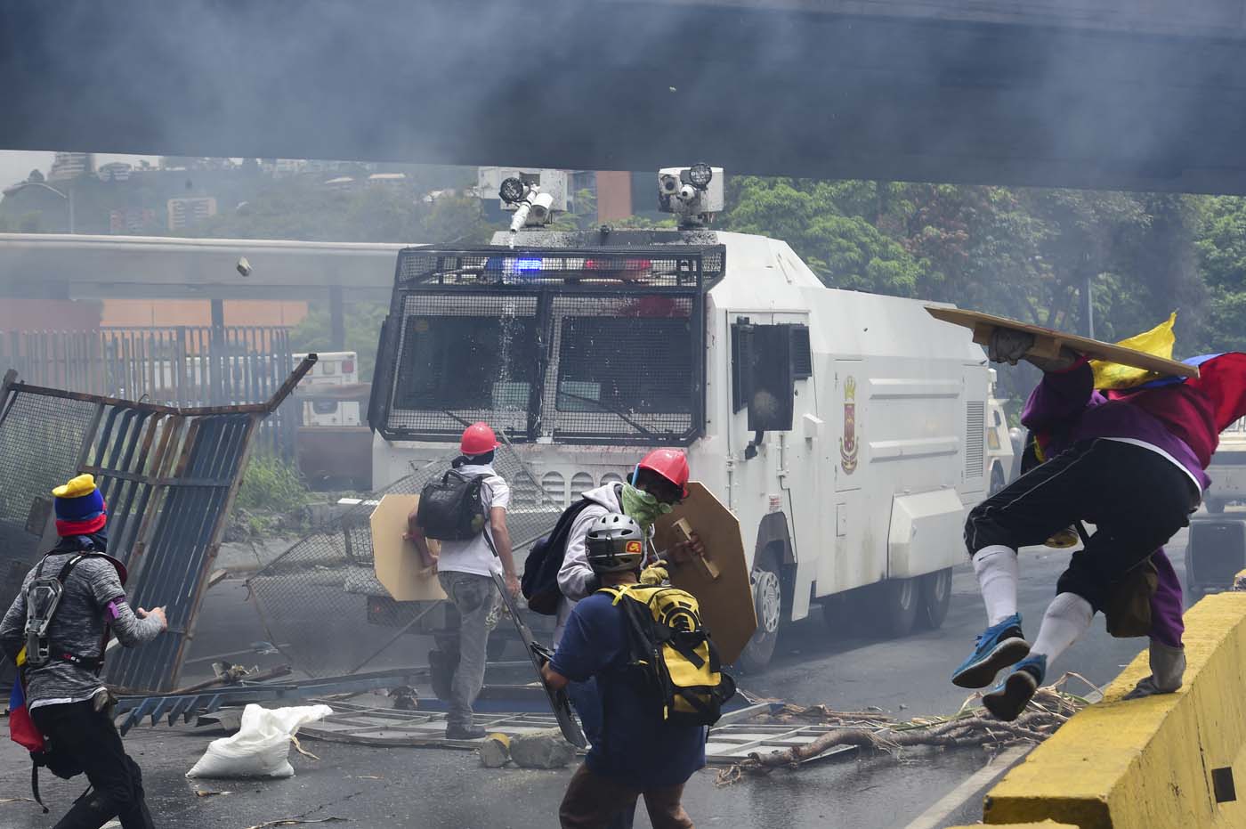 Demonstrators confront a riot police armoured vehicle during clashes within a protest against Venezuelan President Nicolas Maduro, on May 3, 2017. Venezuela's angry opposition rallied Wednesday vowing huge street protests against President Nicolas Maduro's plan to rewrite the constitution and accusing him of dodging elections to cling to power despite deadly unrest. / AFP PHOTO / RONALDO SCHEMIDT