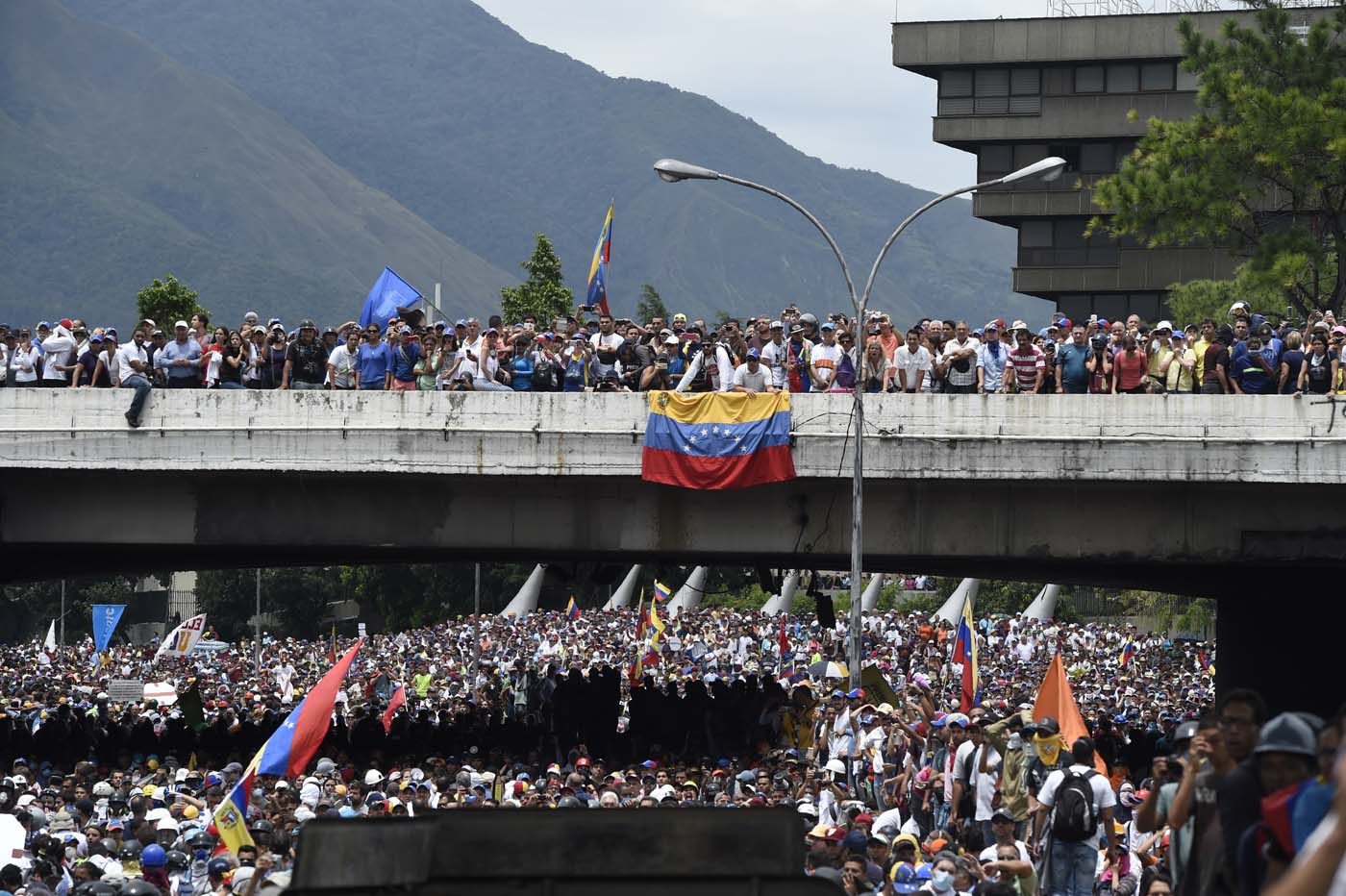 Demonstrators clash with riot police as they march along a major highway of Caracas during a protest against Venezuelan President Nicolas Maduro, on May 3, 2017. Venezuela's angry opposition rallied Wednesday vowing huge street protests against President Nicolas Maduro's plan to rewrite the constitution and accusing him of dodging elections to cling to power despite deadly unrest. / AFP PHOTO / JUAN BARRETO