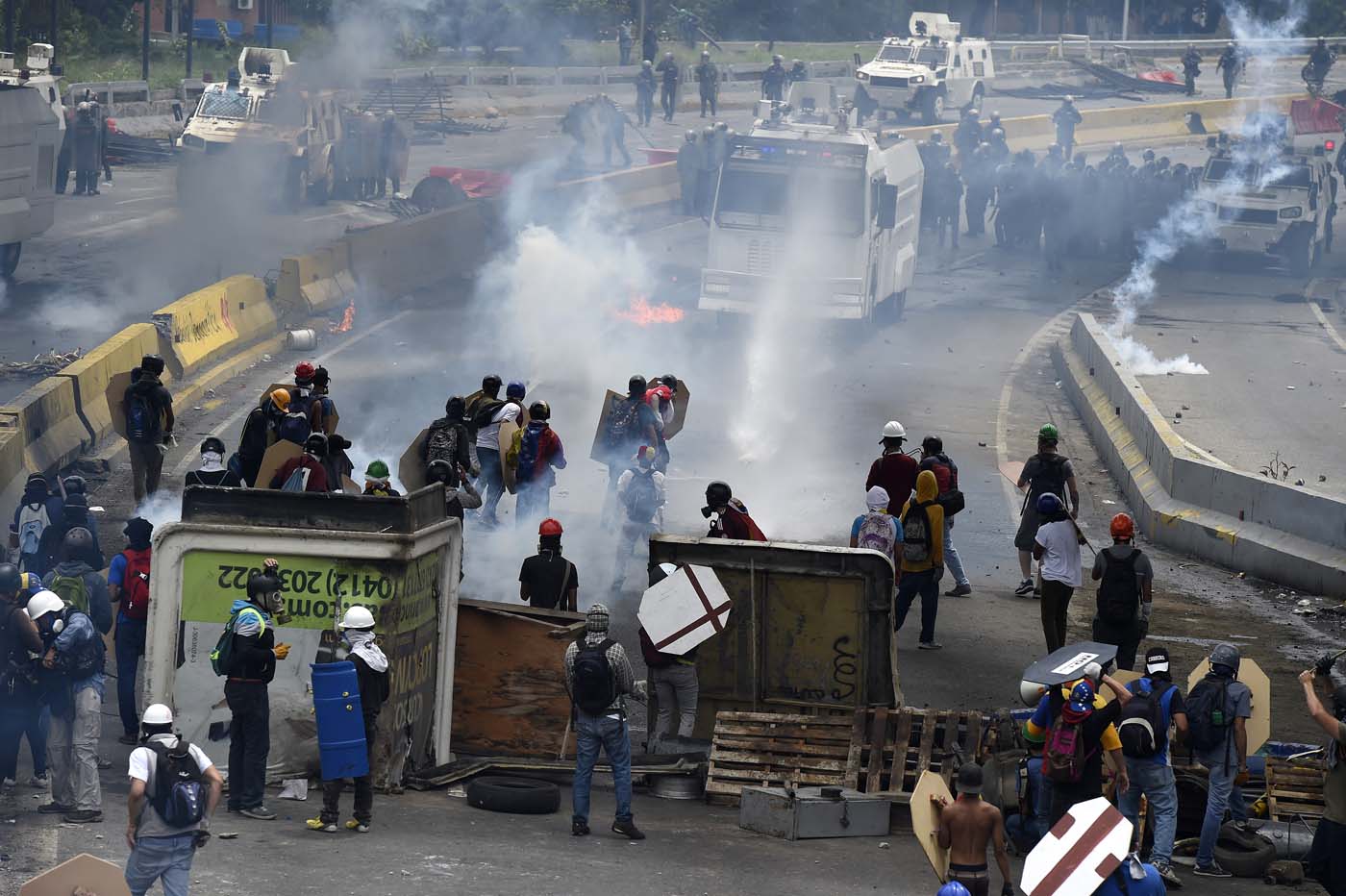 Opposition activists clash with riot police during a protest against Venezuelan President Nicolas Maduro, in Caracas on May 3, 2017. Venezuela's angry opposition rallied Wednesday vowing huge street protests against President Nicolas Maduro's plan to rewrite the constitution and accusing him of dodging elections to cling to power despite deadly unrest. / AFP PHOTO / JUAN BARRETO