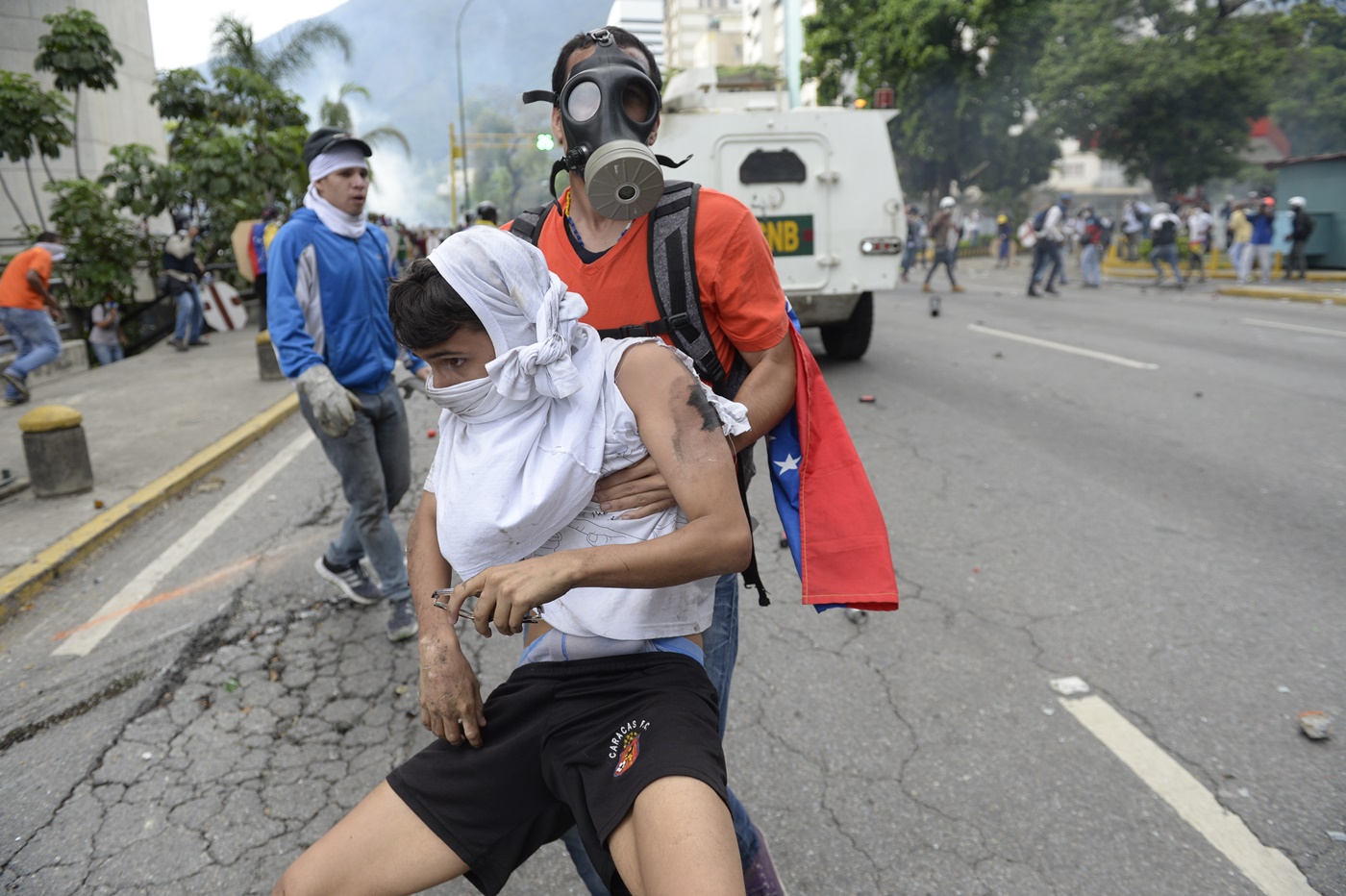 An opposition demonstrator ran over by a National Guard control vehicle is dragged away by a fellow demonstrator during a protest against Venezuelan President Nicolas Maduro, in Caracas on May 3, 2017. Venezuela's angry opposition rallied Wednesday vowing huge street protests against President Nicolas Maduro's plan to rewrite the constitution and accusing him of dodging elections to cling to power despite deadly unrest. / AFP PHOTO / FEDERICO PARRA