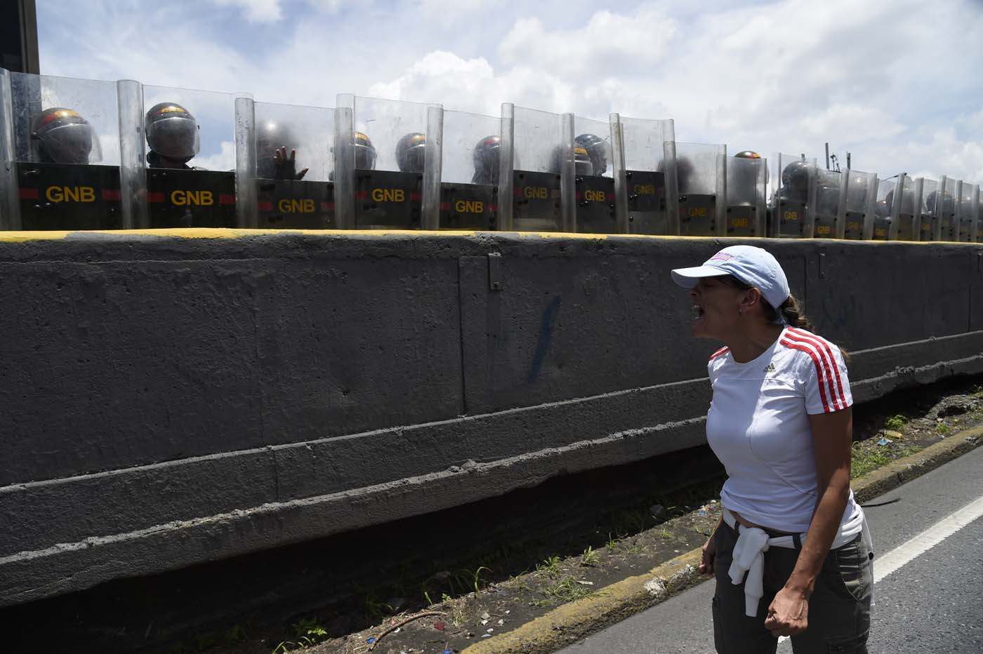 A Venezuelan opposition activist shouts at members of the Bolivarian National Guard standing guard during a women's march aimed to keep pressure on President Nicolas Maduro, whose authority is being increasingly challenged by protests and deadly unrest, in Caracas on May 6, 2017. The death toll since April, when the protests intensified after Maduro's administration and the courts stepped up efforts to undermine the opposition, is at least 36 according to prosecutors. / AFP PHOTO / JUAN BARRETO