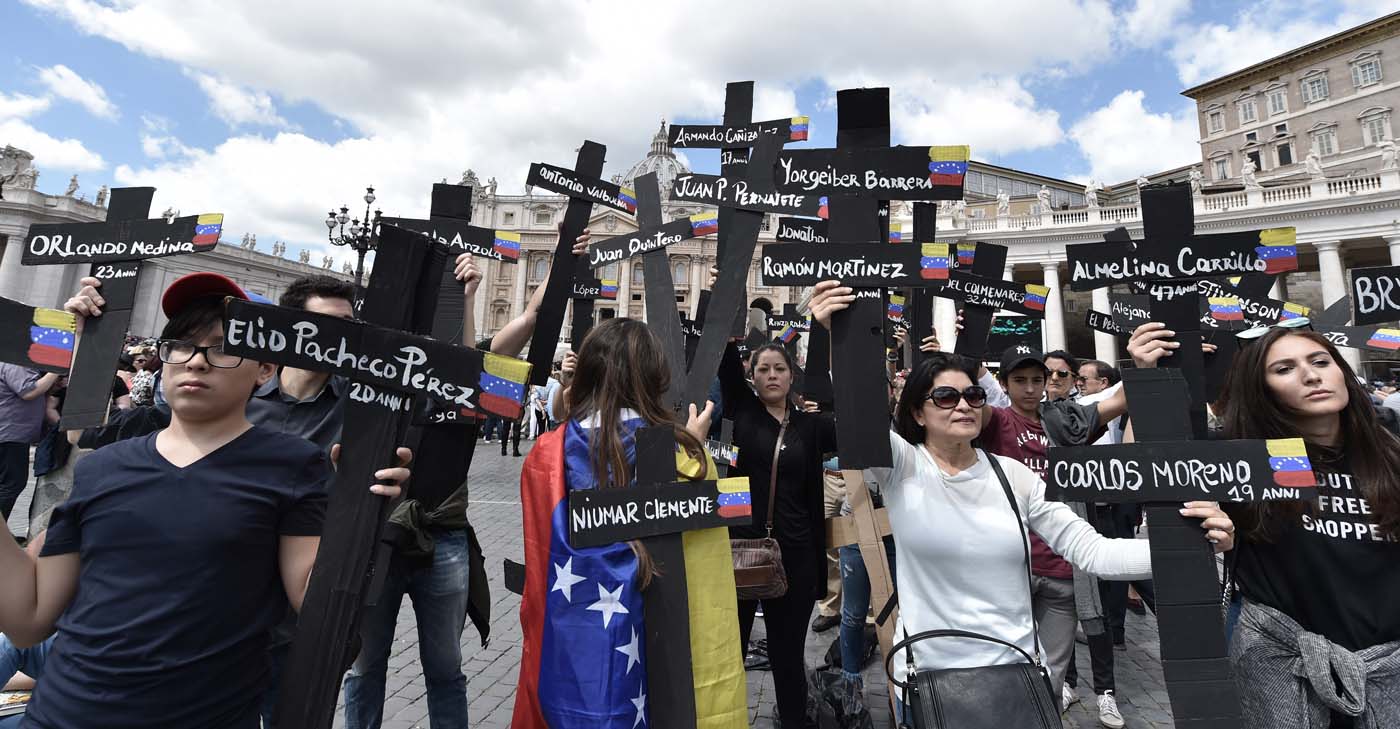 Members of the Venezuelian community hold black crosses with names of victims of clashes with police during protests against Venezuela's President Nicolas Maduro, on May 7, 2017  at St Peter's square before the Regina Coeli prayer of Pope Francis in Vatican. Pope Francis last week made a heartfelt appeal for "negotiated solutions" to end the violence in crisis-torn Venezuela for the sake of an "exhausted population".  The death toll since April -- when the protests intensified after Maduro's administration and the courts stepped up efforts to undermine the opposition -- is at least 36, according to prosecutors, with hundreds more injured. / AFP PHOTO / TIZIANA FABI