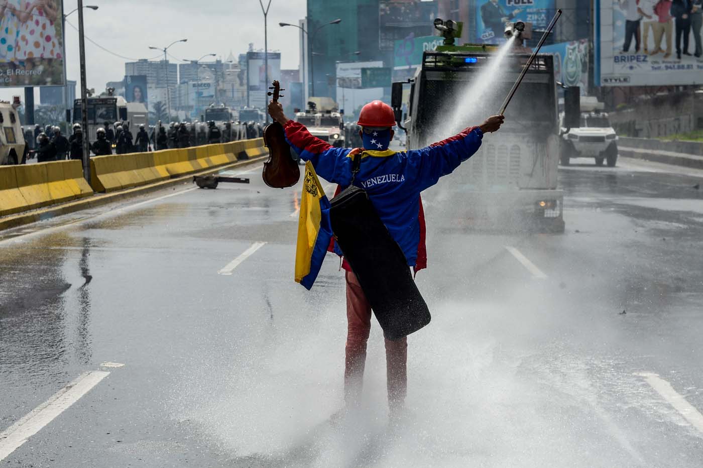 (FILES) This file photo taken on May 24, 2017 shows opposition activist Wuilly Arteaga standing with a violin in front of an armoured vehicle of the riot police during a protest against President Nicolas Maduro in Caracas, on May 24, 2017. "I felt very afraid. I didn't think music had so much power to make people think," he told AFP. "But after the cemetery, I went along to the demonstration with more courage." / AFP PHOTO / FEDERICO PARRA