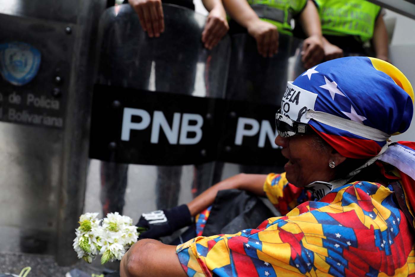 A demonstrator holds flowers next to riot policemen during a women's march to protest against President Nicolas Maduro's government in Caracas, Venezuela, May 6, 2017. REUTERS/Carlos Garcia Rawlins