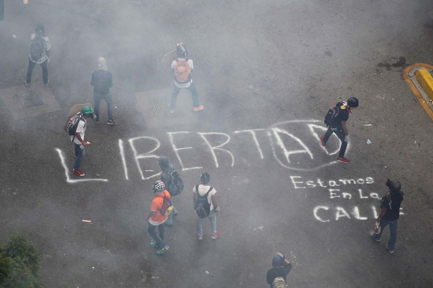 Opposition supporters paint a graffiti that reads "Freedom" while rallying against President Nicolas Maduro in Caracas, Venezuela, May 8, 2017. REUTERS/Christian Veron