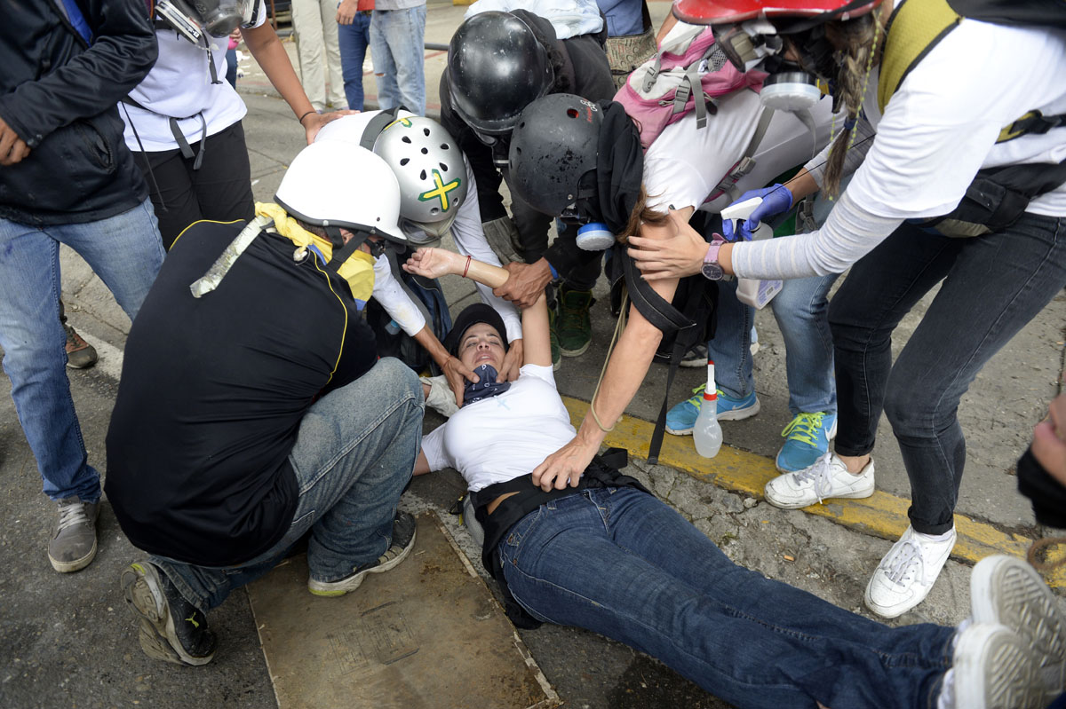 Opposition demonstrators assist an injured fellow activist during the "Towards Victory" protest against the government of President Nicolas Maduro in Caracas on June 10, 2017. Clashes at near daily protests by demonstrators calling for Maduro to quit have left 66 people dead since April 1, prosecutors say. / AFP PHOTO / FEDERICO PARRA