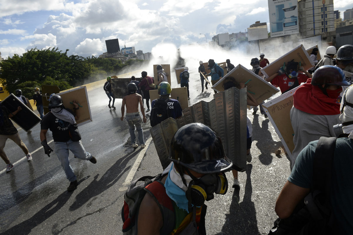 Opposition demonstrators clash with riot police during the "Towards Victory" protest against the government of Nicolas Maduro, in Caracas on June 10, 2017. Clashes at near daily protests by demonstrators calling for Maduro to quit have left 66 people dead since April 1, prosecutors say. / AFP PHOTO / FEDERICO PARRA