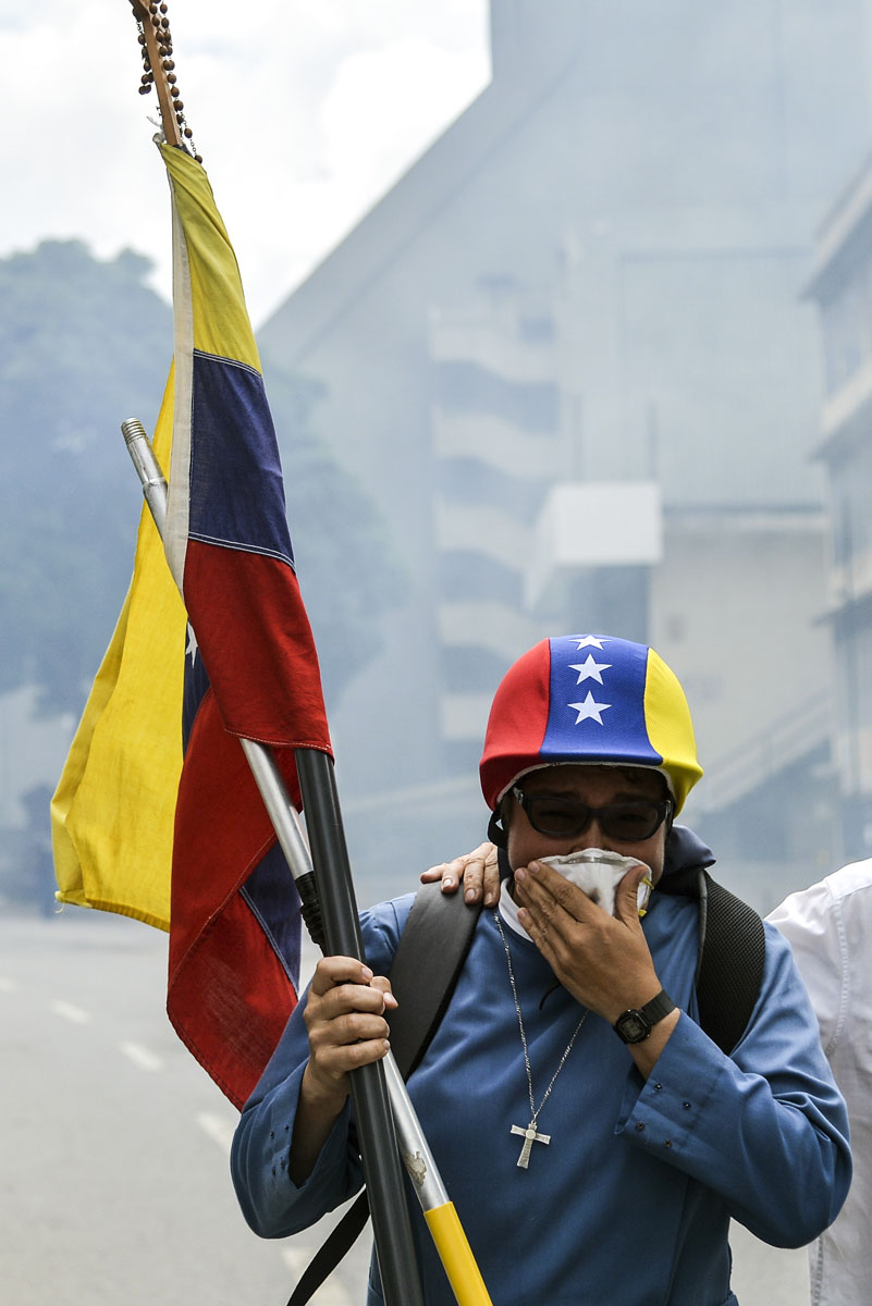 An opposition demonstrator is affected by tear gas in clashes with the riot police during the "Towards Victory" protest against the government of Nicolas Maduro, in Caracas on June 10, 2017. Clashes at near daily protests by demonstrators calling for Maduro to quit have left 66 people dead since April 1, prosecutors say. / AFP PHOTO / LUIS ROBAYO