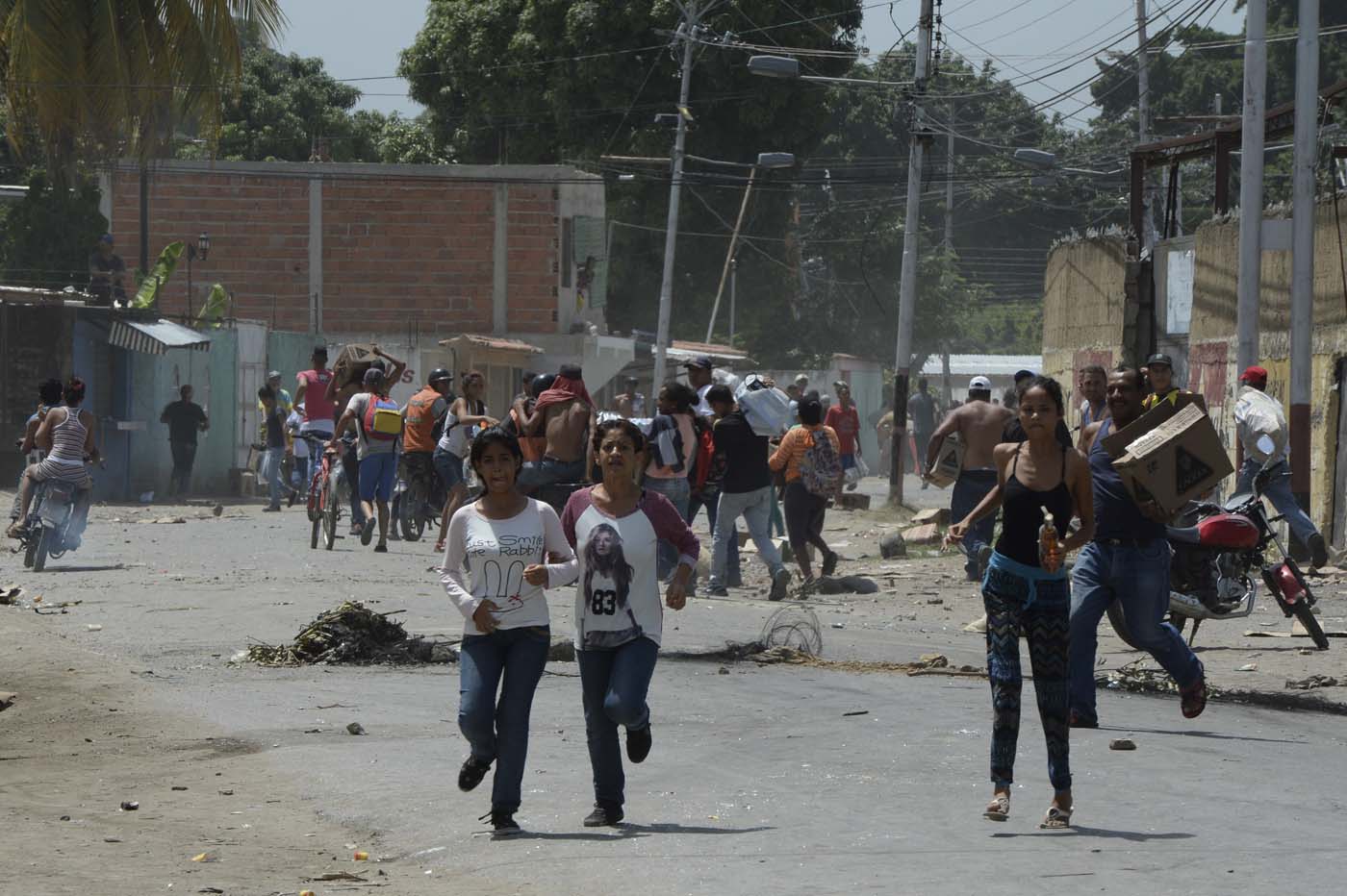 Locals run carrying stolen merchandise during lootings in Maracay, Aragua state, Venezuela on June 27, 2017. / AFP PHOTO / Federico Parra