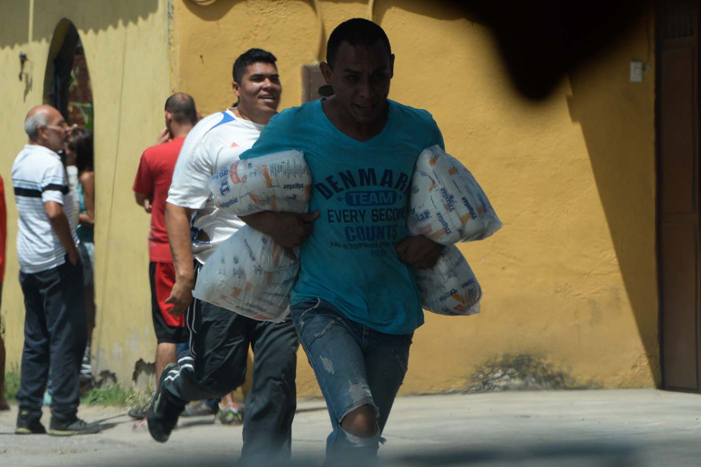 People carry stolen merchandise during lootings in Maracay, Aragua State, Venezuela on June 27, 2017. A political and economic crisis in the oil-producing country has spawned often violent demonstrations by protesters demanding President Nicolas Maduro's resignation and new elections. The unrest has left 76 people dead since April 1. / AFP PHOTO / Federico PARRA