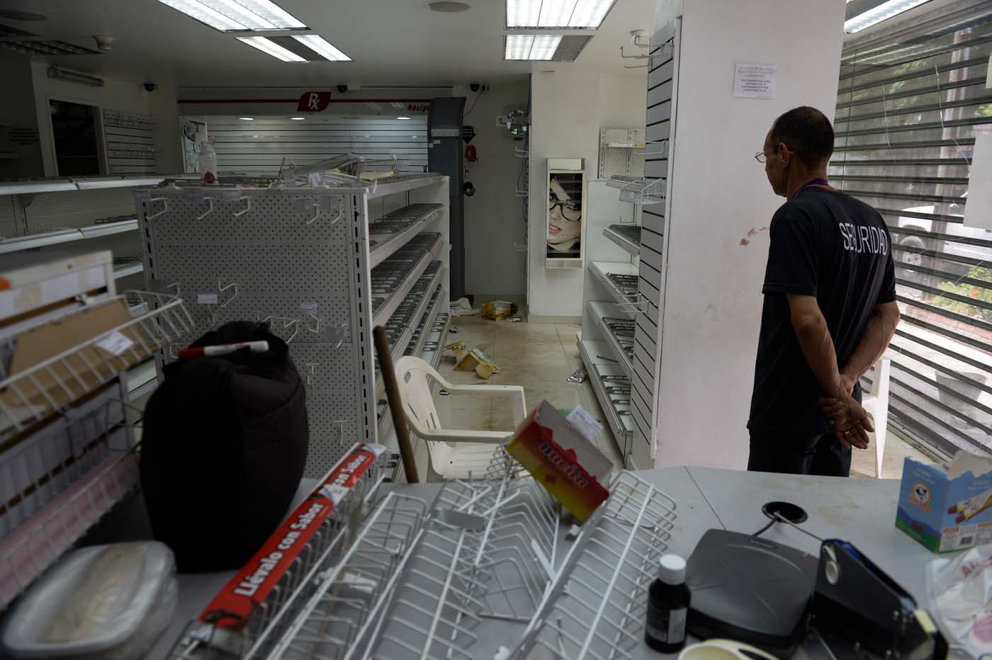 A security guard remains inside a looted pharmacy in Maracay, Aragua state, Venezuela on June 27, 2017. / AFP PHOTO / FEDERICO PARRA
