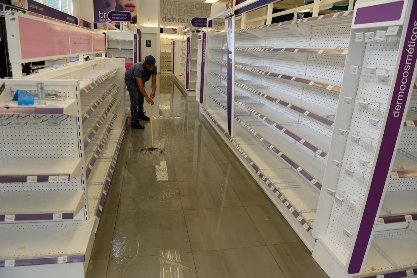 Employees clean the aisles in a looted pharmacy in Maracay, Aragua state, Venezuela on June 27, 2017. / AFP PHOTO / FEDERICO PARRA