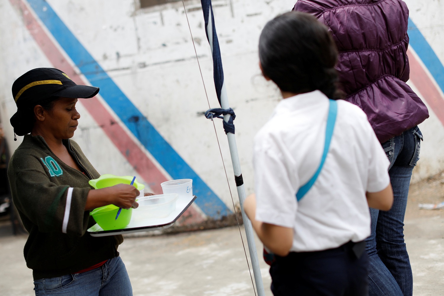 Un voluntario de la oposición que trabaja como voluntarios recolecta contenedores de plástico para servir la comida en un comedor para niños, en el barrio La Vega de Caracas, Venezuela, el 23 de mayo de 2017. Foto tomada el 23 de mayo de 2017. REUTERS / Carlos Garcia Rawlins
