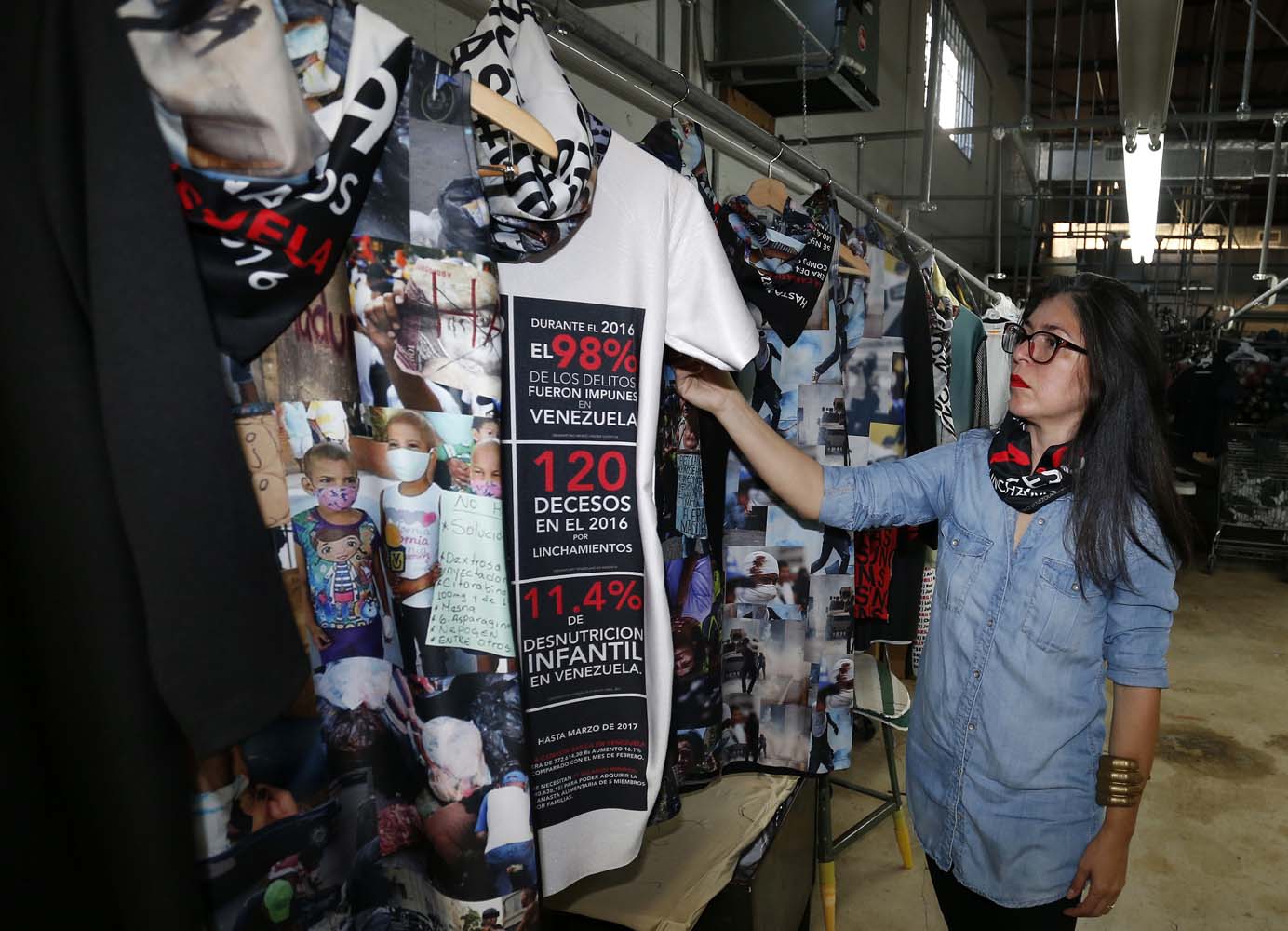 Venezuelan artist and designer Lisu Vega stands with her collection "Resistance" in a warehouse in Miami, Florida on June 8, 2017. The models are dressed in scenes of violence in Caracas and handkerchiefs representing the rags used by protesters to protect themselves from police tear gas. It is the "Resistance" collection of Venezuelan fashion designer Lisu Vega. / AFP PHOTO / RHONA WISE