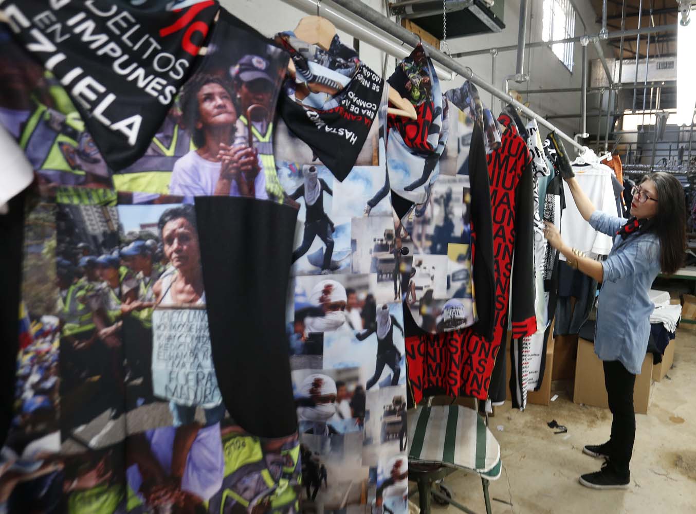 Venezuelan artist and designer Lisu Vega stands with her collection "Resistance" in a warehouse in Miami, Florida on June 8, 2017. The models are dressed in scenes of violence in Caracas and handkerchiefs representing the rags used by protesters to protect themselves from police tear gas. It is the "Resistance" collection of Venezuelan fashion designer Lisu Vega. / AFP PHOTO / RHONA WISE