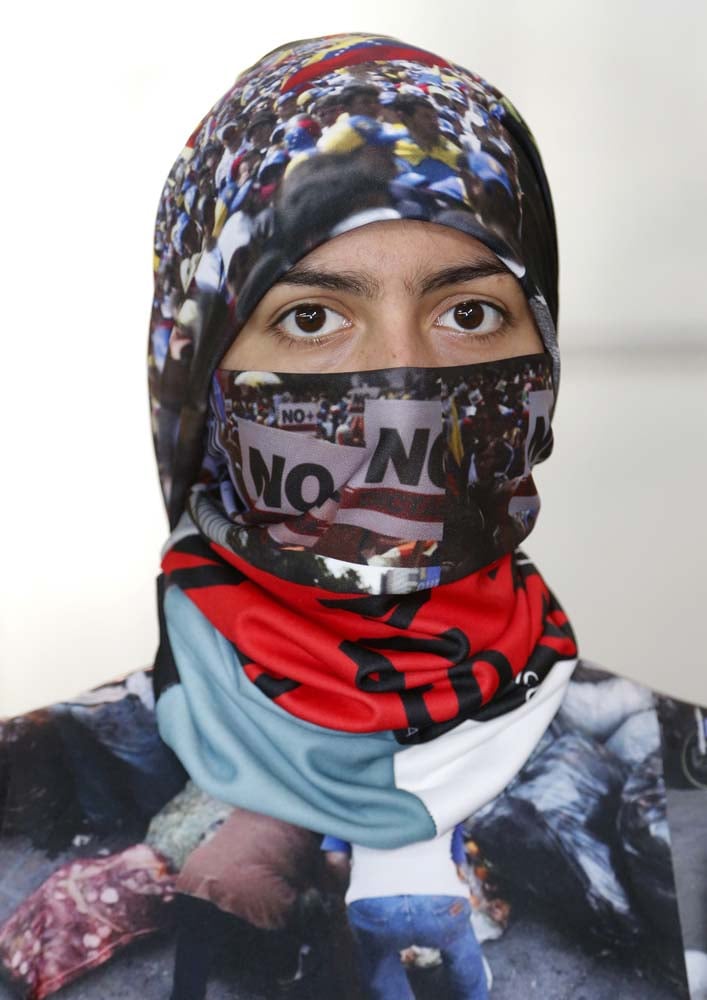 Vida Delgato models a head scarf by Venezuelan artist and designer Lisu Vega from her collection "Resistance" in a warehouse in Miami, Florida on June 8, 2017. The models are dressed in scenes of violence in Caracas and handkerchiefs representing the rags used by protesters to protect themselves from police tear gas. It is the "Resistance" collection of Venezuelan fashion designer Lisu Vega. / AFP PHOTO / RHONA WISE