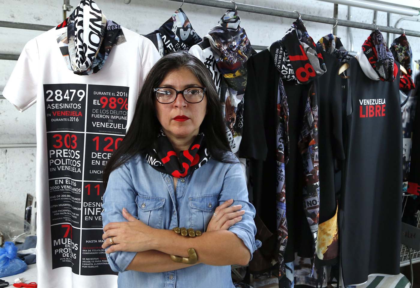 Venezuelan artist and designer Lisu Vega poses in front of her collection "Resistance" in a warehouse in Miami, Florida on June 8, 2017. The models are dressed in scenes of violence in Caracas and handkerchiefs representing the rags used by protesters to protect themselves from police tear gas. It is the "Resistance" collection of Venezuelan fashion designer Lisu Vega. / AFP PHOTO / RHONA WISE