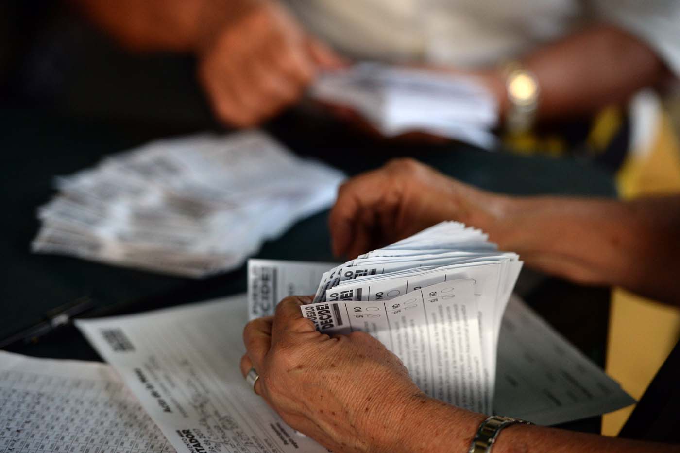 Volunteers count the ballots during an opposition-organized vote to measure public support for Venezuelan President Nicolas Maduro's plan to rewrite the constitution in Caracas on July 16, 2017. Authorities have refused to greenlight the vote that has been presented as an act of civil disobedience and supporters of Maduro are boycotting it. Protests against Maduro since April 1 have brought thousands to the streets demanding elections, but has also left 95 people dead, according to an official toll.  / AFP PHOTO / Federico Parra