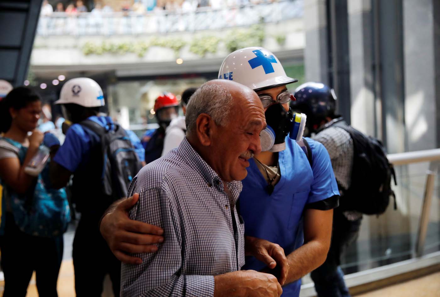 A man is helped as he leaves a shopping mall after smoke from tear gas fired by security forces got inside of it during clashes at a rally against Venezuelan President Nicolas Maduro's government in Caracas, Venezuela, July 6, 2017. REUTERS/Carlos Garcia Rawlins