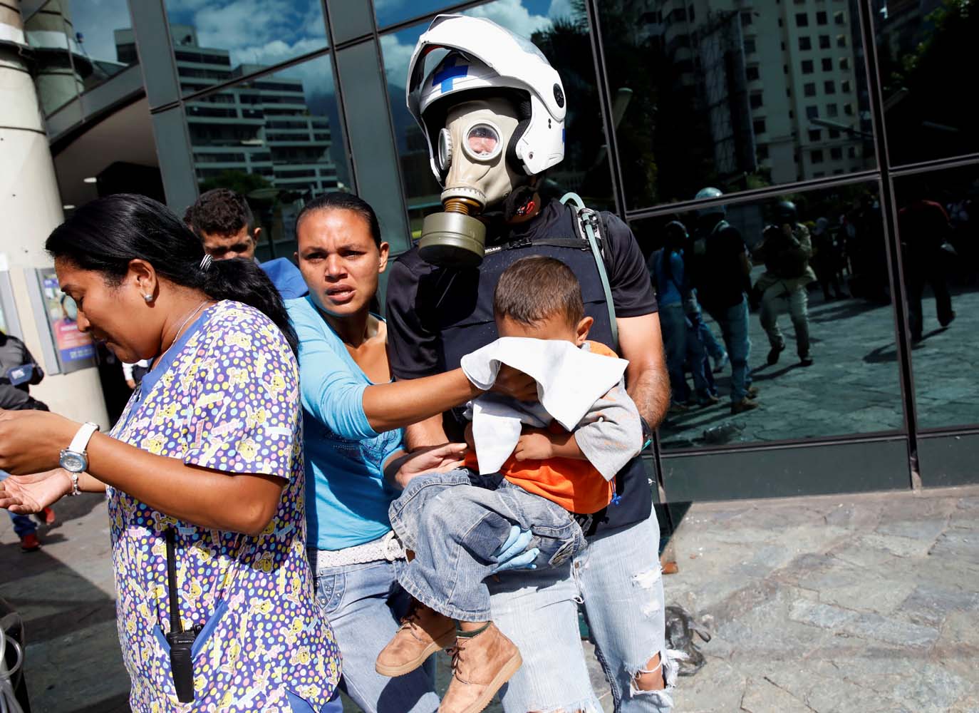 A man carries a child out of a shopping mall after smoke from tear gas fired by security forces got inside of it during clashes at a rally against Venezuelan President Nicolas Maduro's government in Caracas, Venezuela, July 6, 2017. REUTERS/Carlos Garcia Rawlins