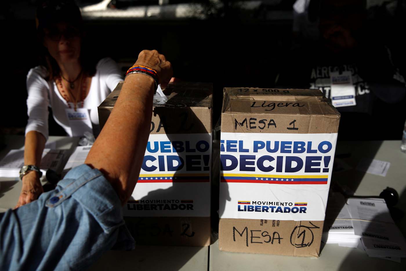 A person votes during an unofficial plebiscite against Venezuela's President Nicolas Maduro's government and his plan to rewrite the constitution, in Caracas, Venezuela July 16, 2017. The writing on the boxes read "The people decide, Liberator Movement." REUTERS/Carlos Garcia Rawlins