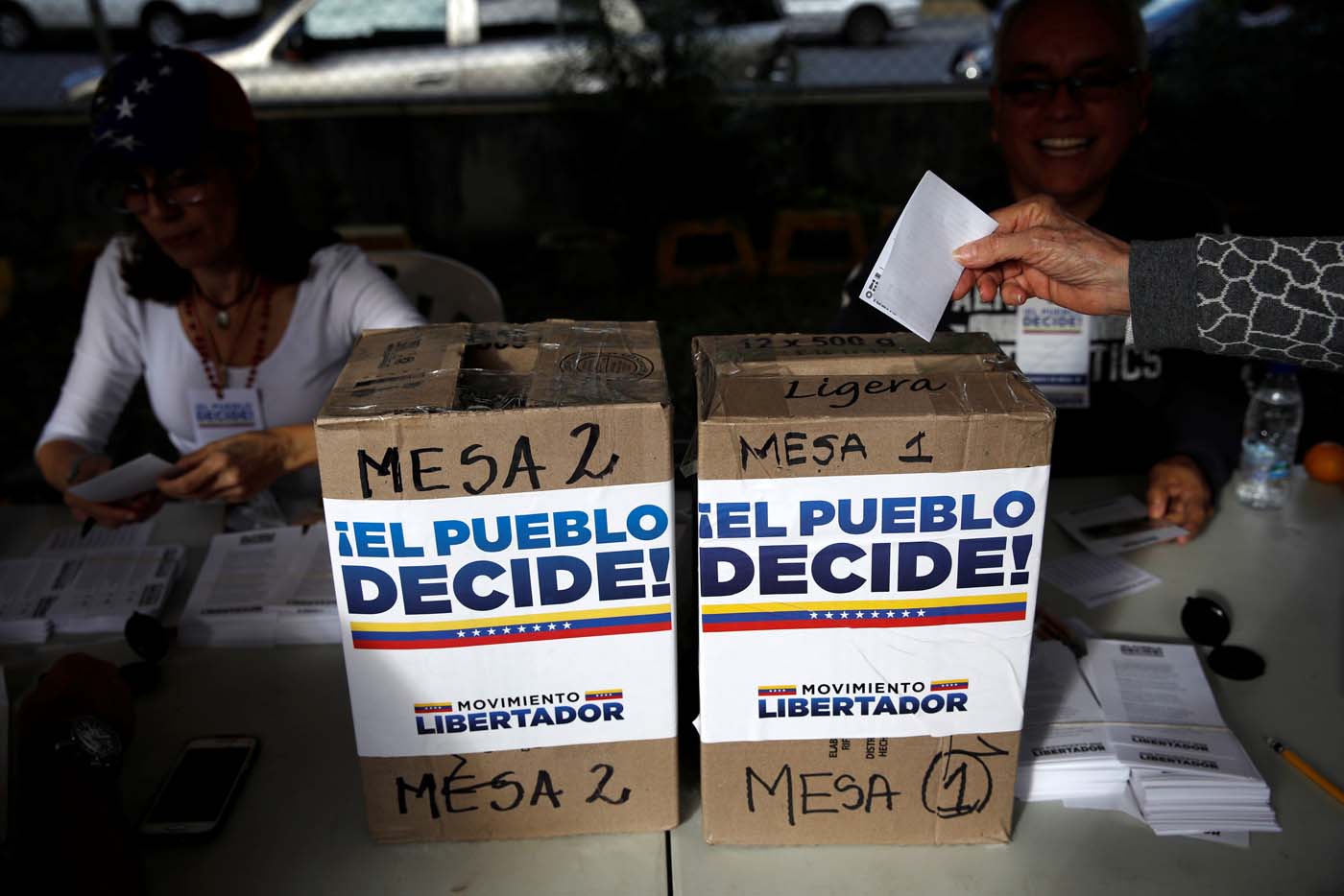 A woman casts her vote during an unofficial plebiscite against Venezuela's President Nicolas Maduro's government and his plan to rewrite the constitution, in Caracas, Venezuela July 16, 2017. The writing on the boxes read "The people decide, Liberator Movement." REUTERS/Carlos Garcia Rawlins
