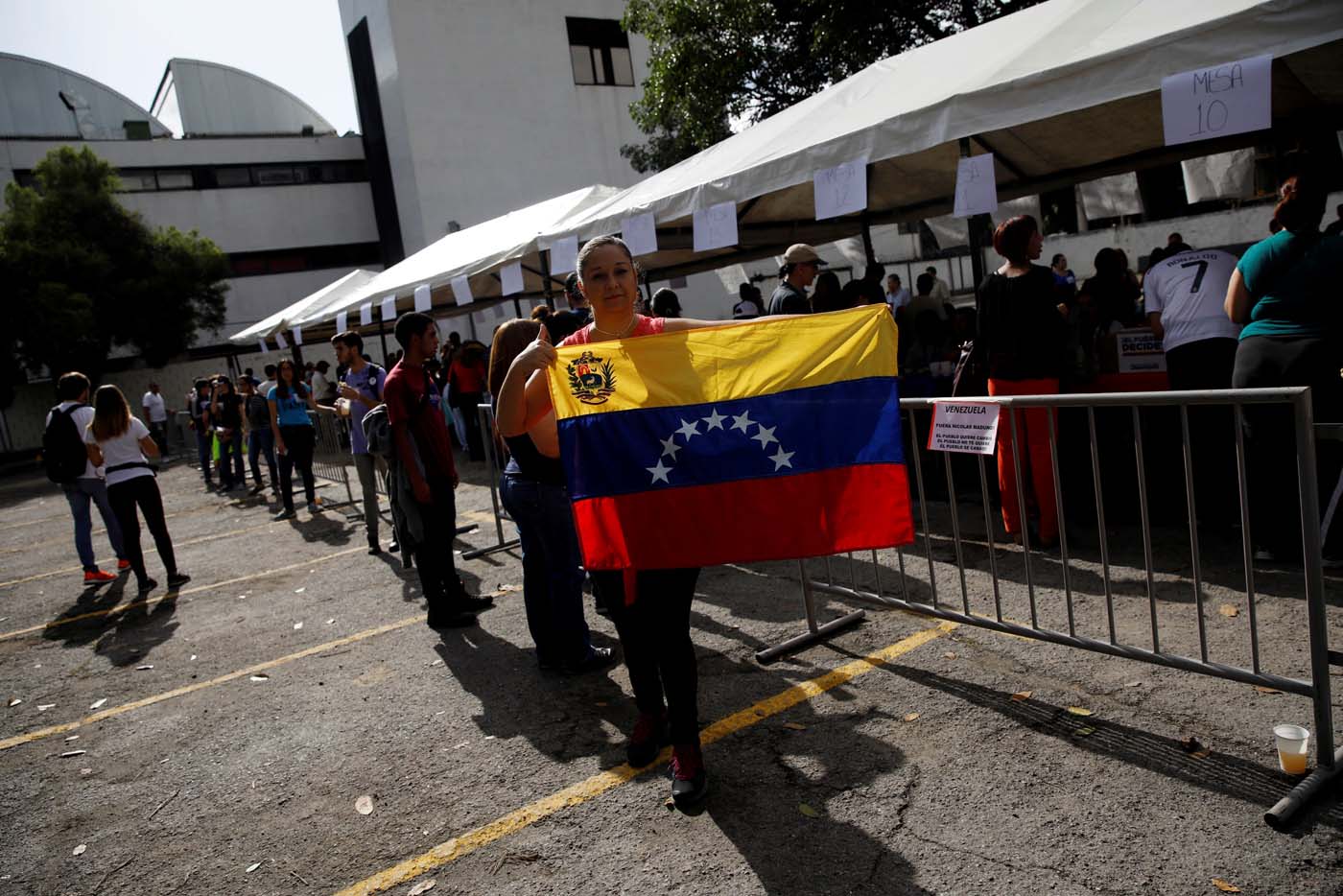A woman holds a national flag at a polling station during an unofficial plebiscite against Venezuela's President Nicolas Maduro's government and his plan to rewrite the constitution, in Caracas, Venezuela July 16, 2017. REUTERS/Carlos Garcia Rawlins