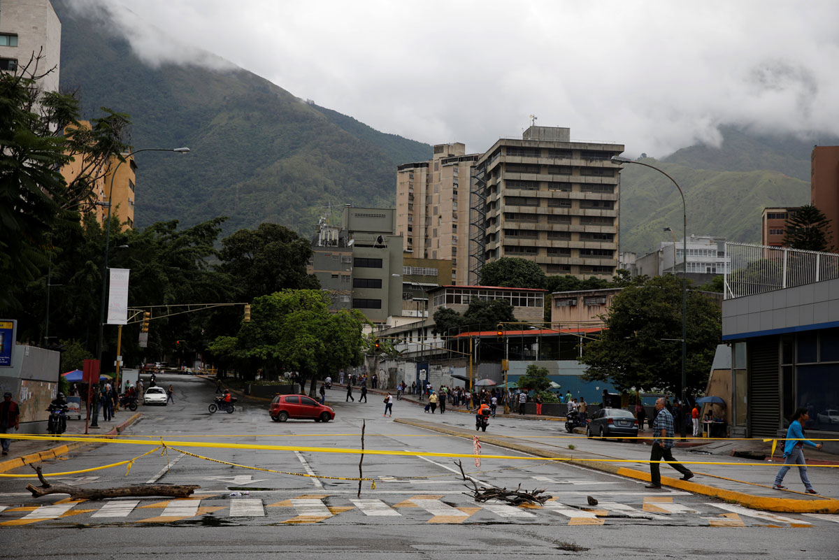 Pedestrians walk past a barricade during a rally against Venezuelan President Nicolas Maduro's government in Caracas, Venezuela, July 19, 2017.  REUTERS/Carlos Garcia Rawlins