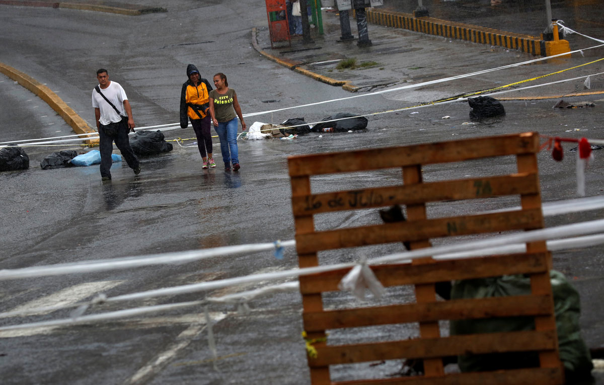 Pedestrians walk past a barricade during a rally against Venezuelan President Nicolas Maduro's government in Caracas, Venezuela, July 19, 2017.  REUTERS/Carlos Garcia Rawlins