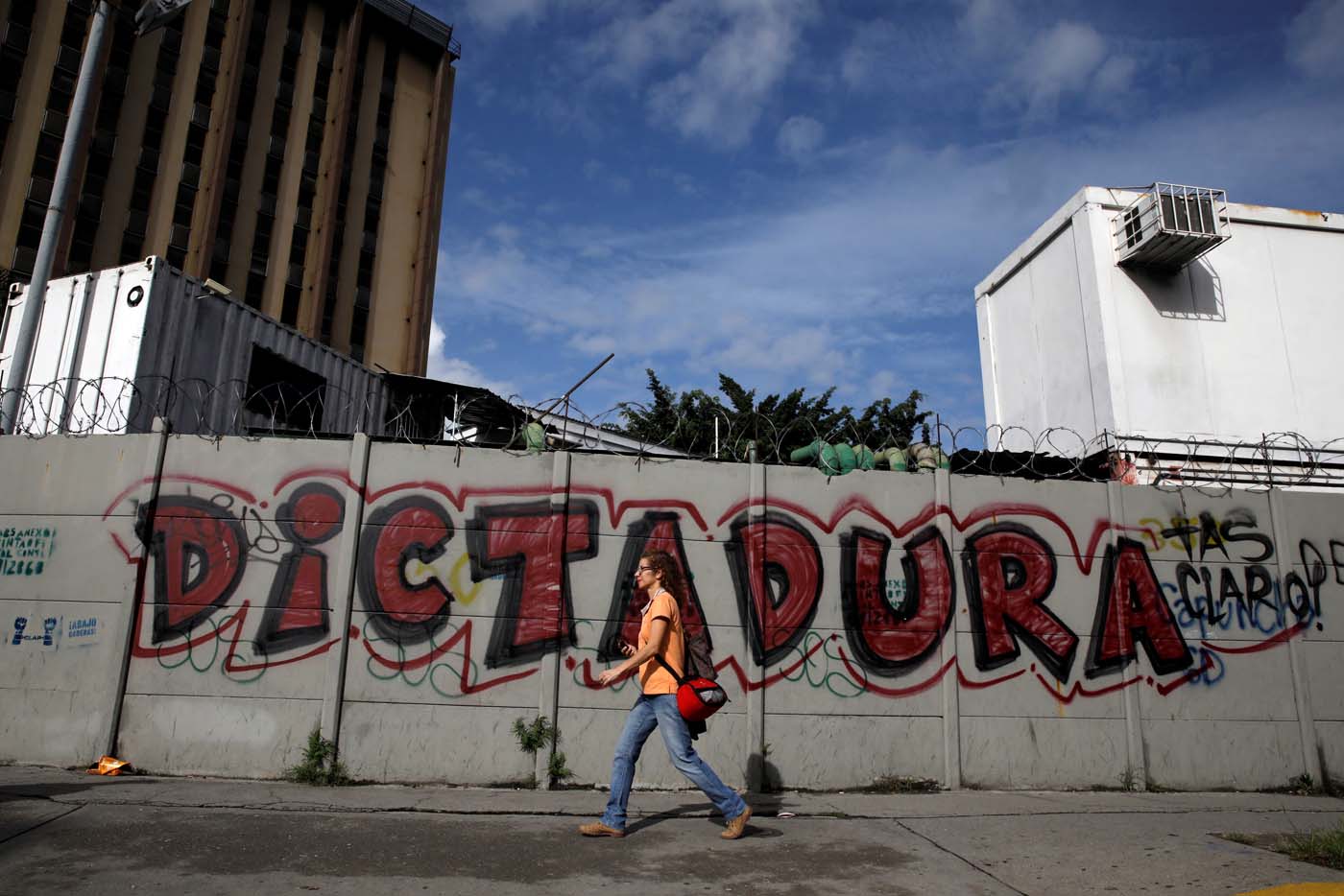 A woman walks in front of a graffiti that reads "Dictatorship" during a strike called to protest against Venezuelan President Nicolas Maduro's government in Caracas, Venezuela, July 20, 2017. REUTERS/Carlos Garcia Rawlins