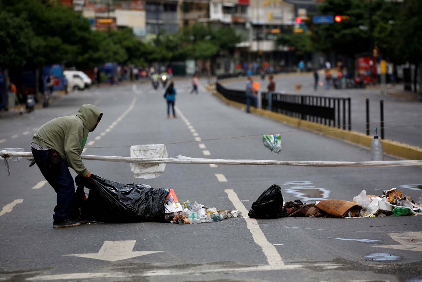 A man uses garbage to block a street during a strike called to protest against Venezuelan President Nicolas Maduro's government in Caracas, Venezuela, July 20, 2017. REUTERS/Carlos Garcia Rawlins