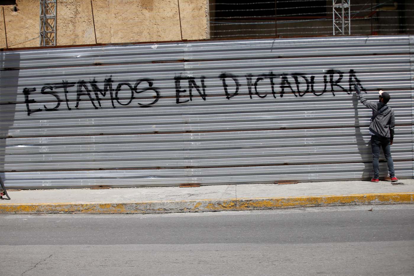 A demonstrator paints a graffiti that reads "we are in a dictatorship" during a strike called to protest against Venezuelan President Nicolas Maduro's government in Caracas, Venezuela, July 20, 2017. REUTERS/Andres Martinez Casares