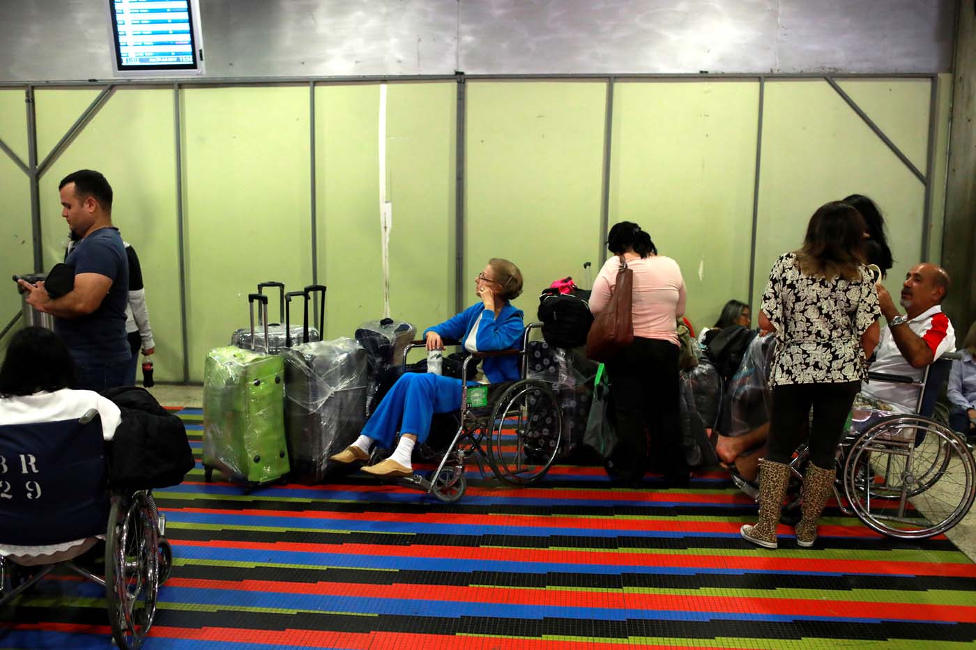 People wait by a counter of Avianca airline, at the Simon Bolivar airport in Caracas, Venezuela July 27, 2017. REUTERS/Marco Bello