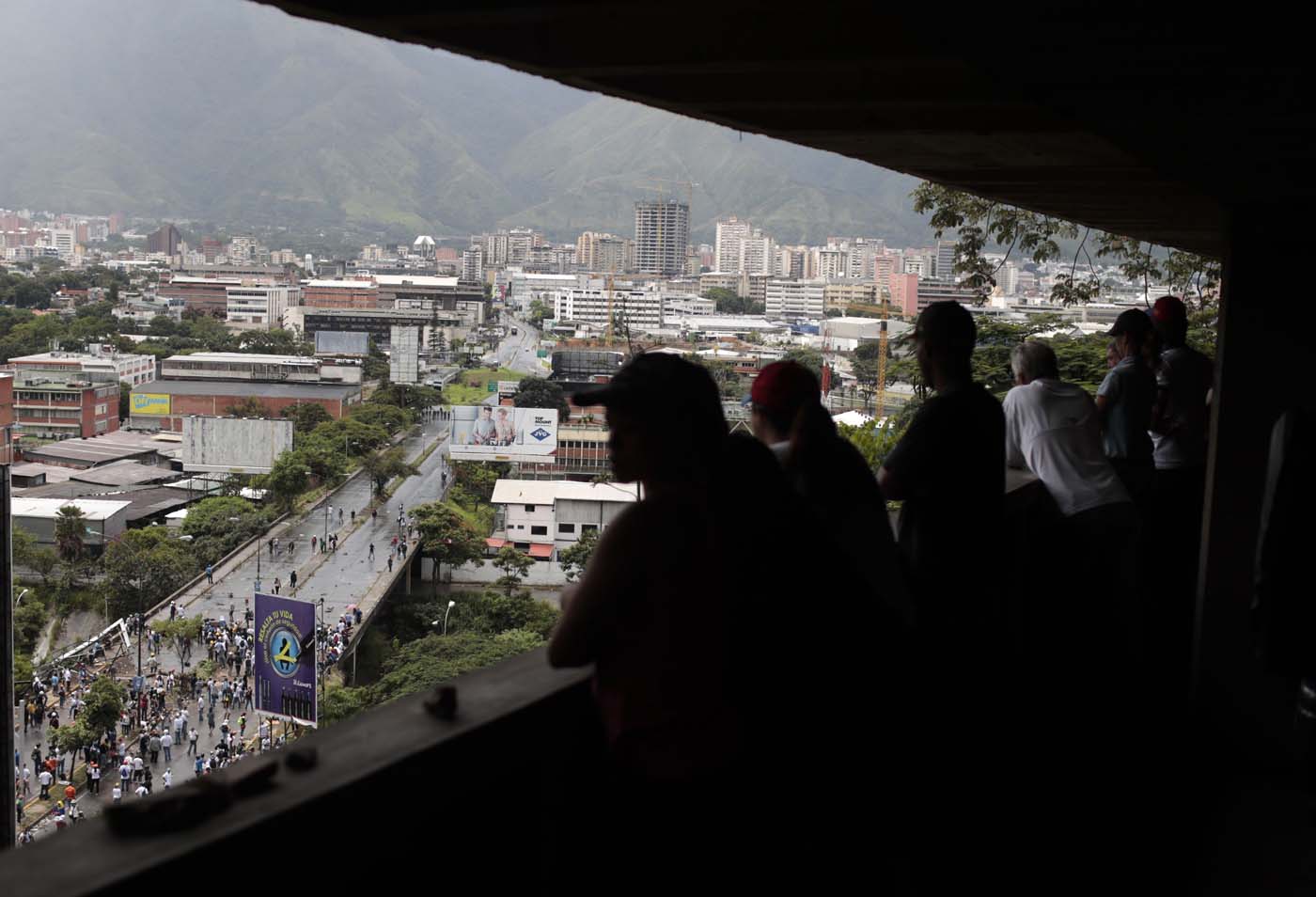 People watch from a balcony as opposition demonstrators set up a barricade on a bridge as clashes broke out with security forces while the Constituent Assembly election was being carried out in Caracas, Venezuela, July 30, 2017. REUTERS/Marco Bello