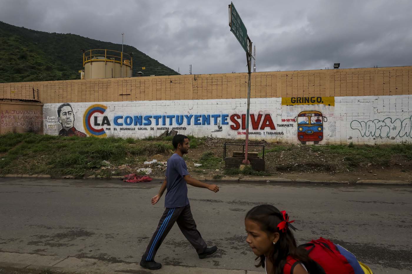 ACOMPAÑA CRÓNICA: VENEZUELA CRISIS - CAR002. CARACAS (VENEZUELA), 15/07/2017.- Un hombre y una niña caminan en frente de una pared decorada con propaganda de la Asamblea Nacional Constituyente en una barriada hoy, sábado 15 de julio de 2017, en Caracas (Venezuela). Con el éxito asegurado en las zonas privilegiadas de Caracas, donde el chavismo nunca tuvo predicamento, la consulta opositora sobre la Asamblea Constituyente que impulsa el presidente Nicolás Maduro se la juega ahora en los barrios populares que vieron en Hugo Chávez el mesías de la Revolución Bolivariana. EFE/Miguel Gutiérrez