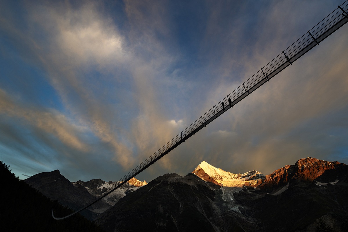 A couple walks on the "Europabruecke",  supposed to be the world's longest pedestrian suspension bridge with a length of 494m, prior to the official inauguration of the construction in Randa, Switzerland, on Saturday, July 29, 2017. The bridge is situated on the Europaweg that connects the villages of Zermatt and Graechen. (Valentin Flauraud/Keystone via AP)