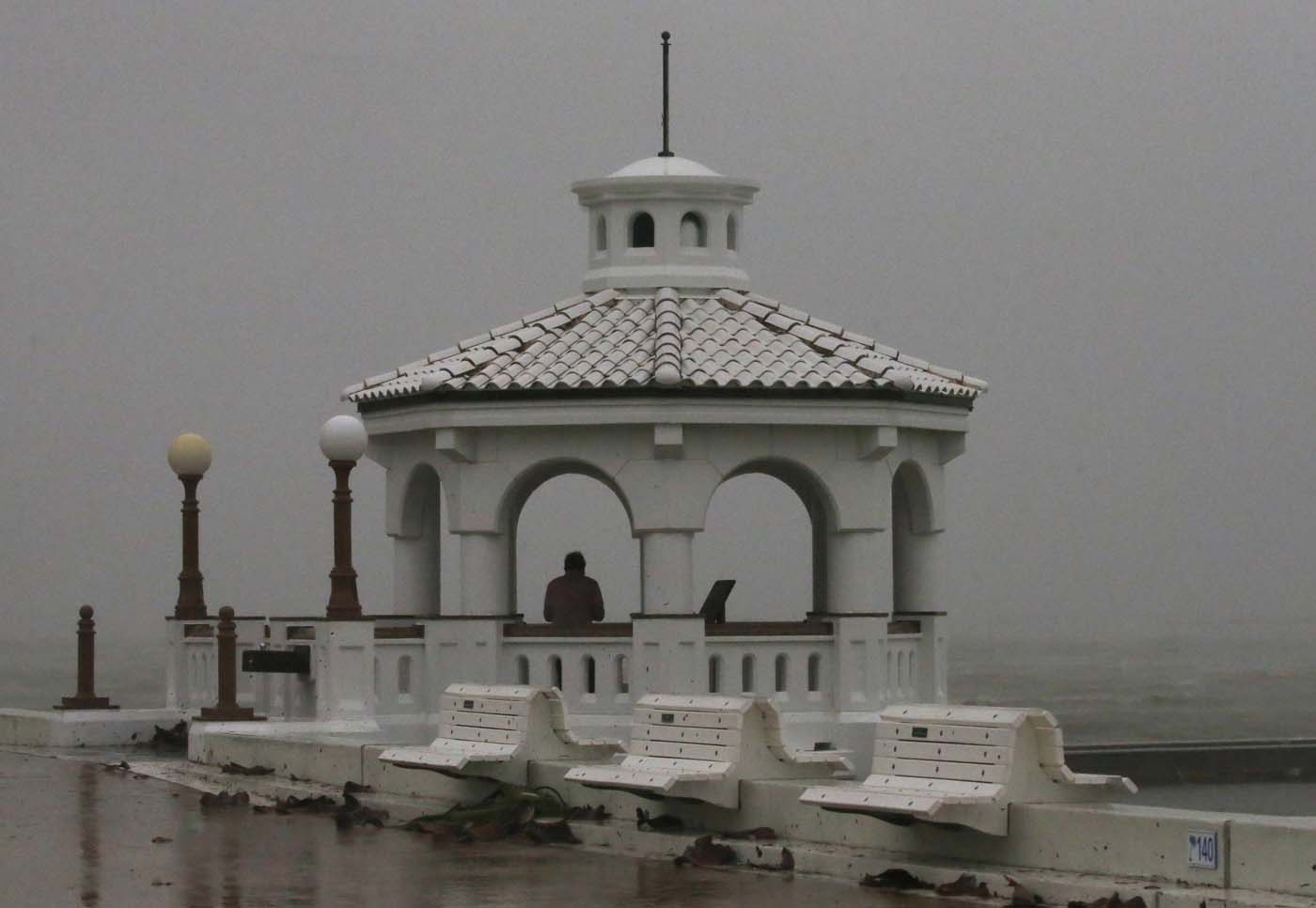 A man standing in a gazebo watches the surf of the approaching Hurricane Harvey on the boardwalk in Corpus Christi, Texas, U.S. August 25, 2017. REUTERS/Adrees Latif